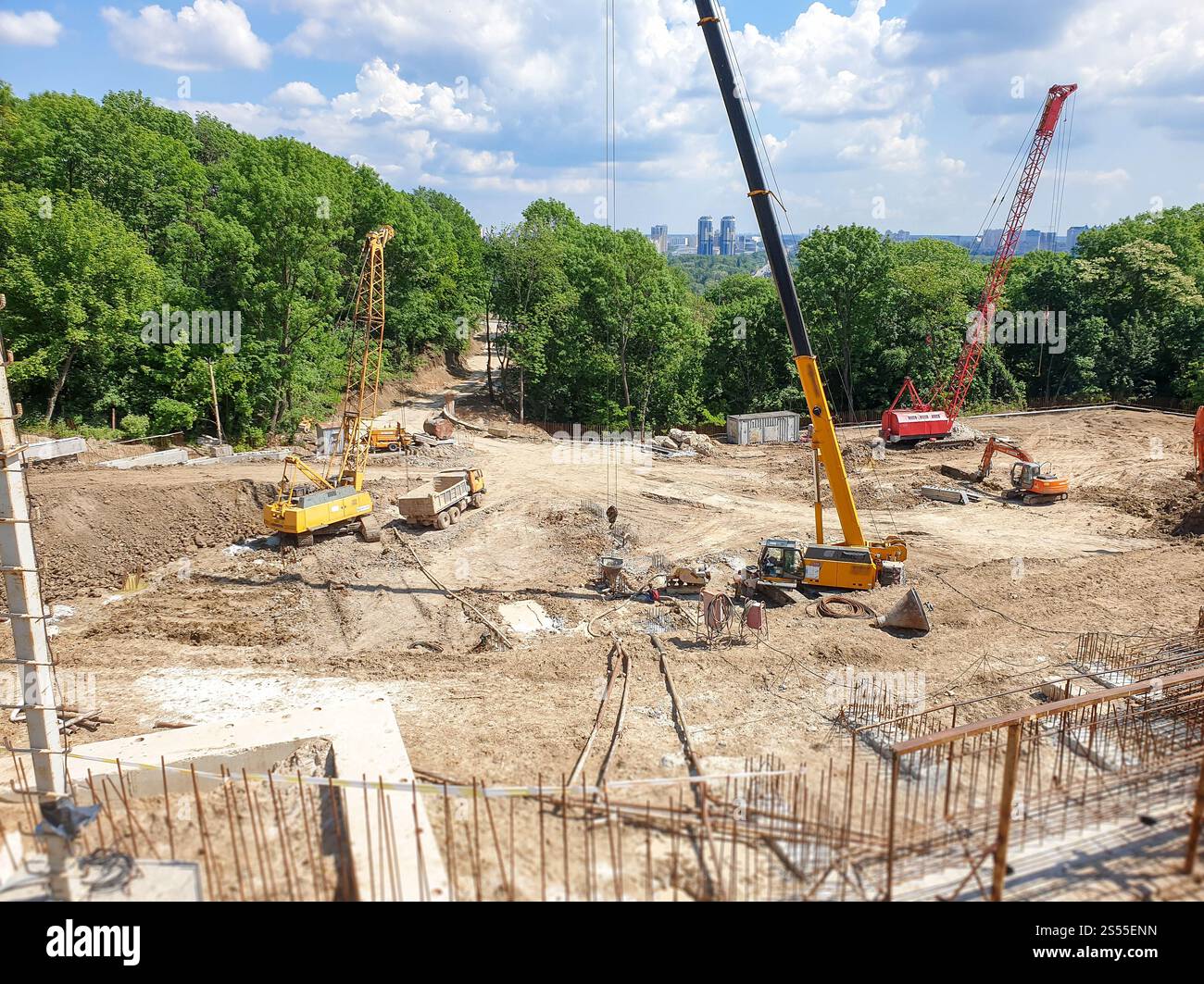 Photo de camions lourds et de grues de construction travaillant sur le chantier par jour ensoleillé. Image de camions lourds et de grues de construction travaillant sur le Banque D'Images