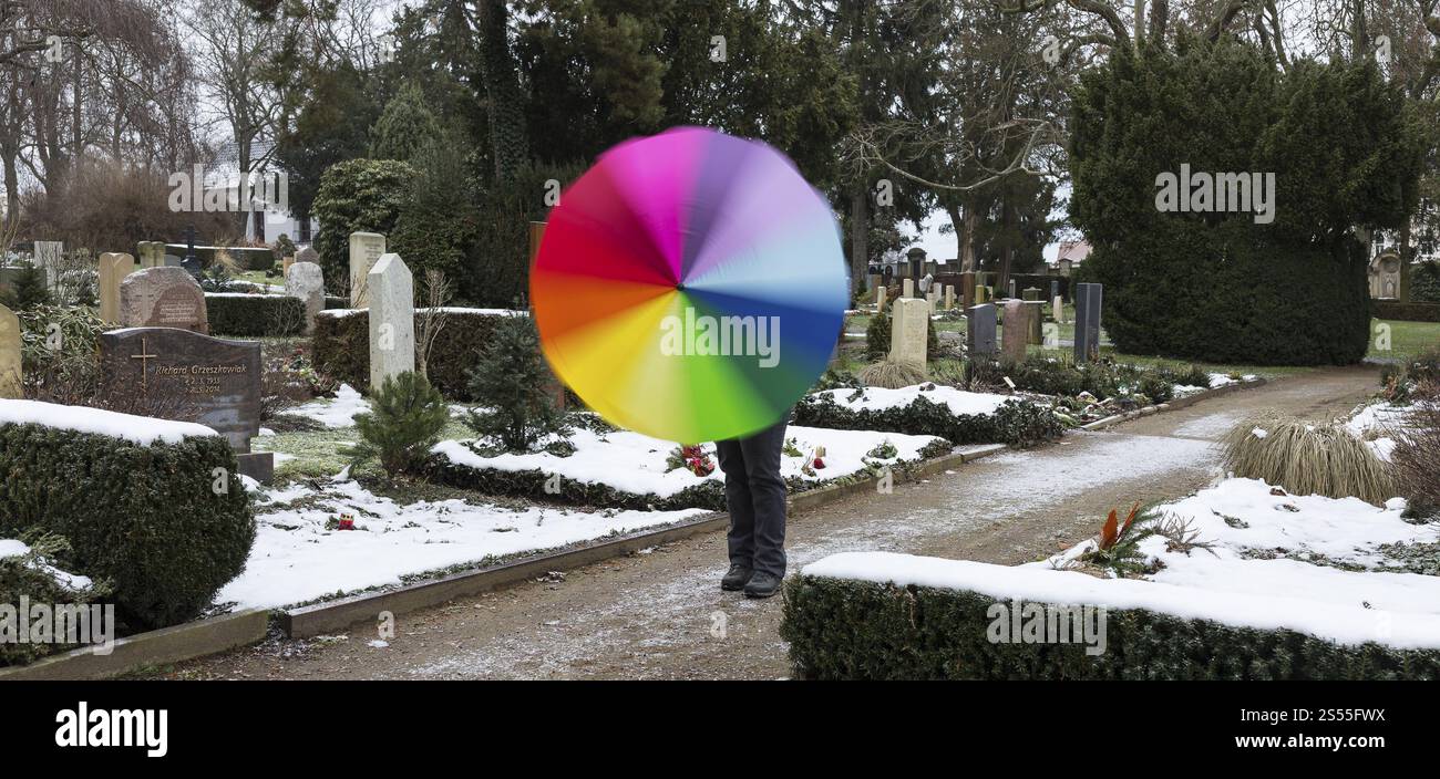 Homme avec un parapluie coloré par temps gris entre les tombes, cimetière de Riesa, Saxe, Allemagne, Europe Banque D'Images
