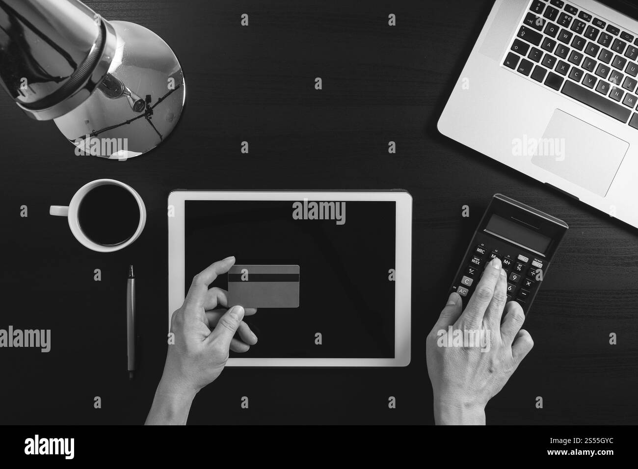 Concept d'achat sur Internet. Vue de dessus des mains travaillant avec ordinateur portable et carte de crédit et tablette sur fond de table en bois foncé, noir et blanc Banque D'Images