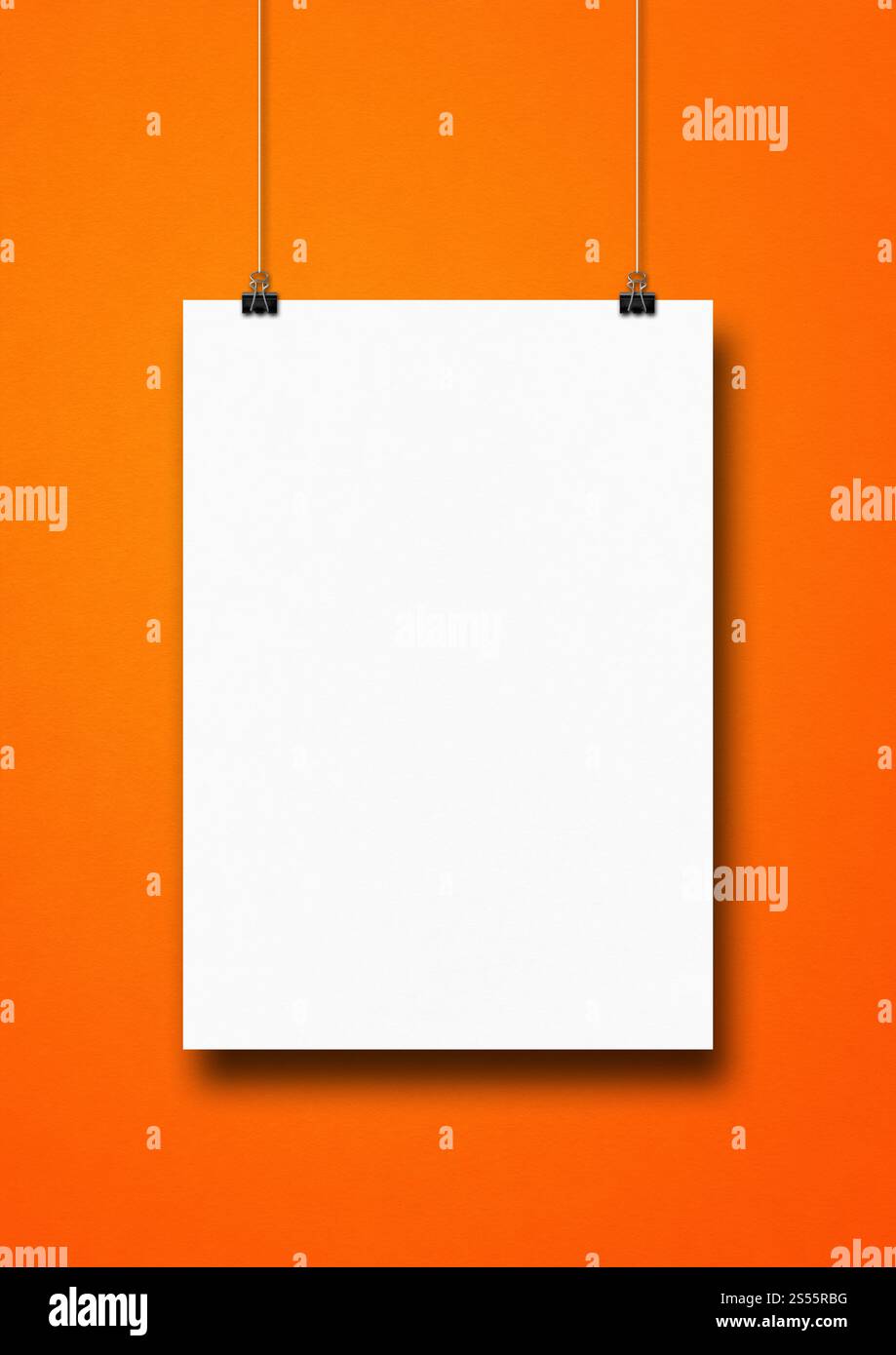 Affiche blanche accrochée sur un mur orange avec des clips. Modèle de maquette vierge. Affiche blanche accrochée sur un mur orange avec des clips Banque D'Images
