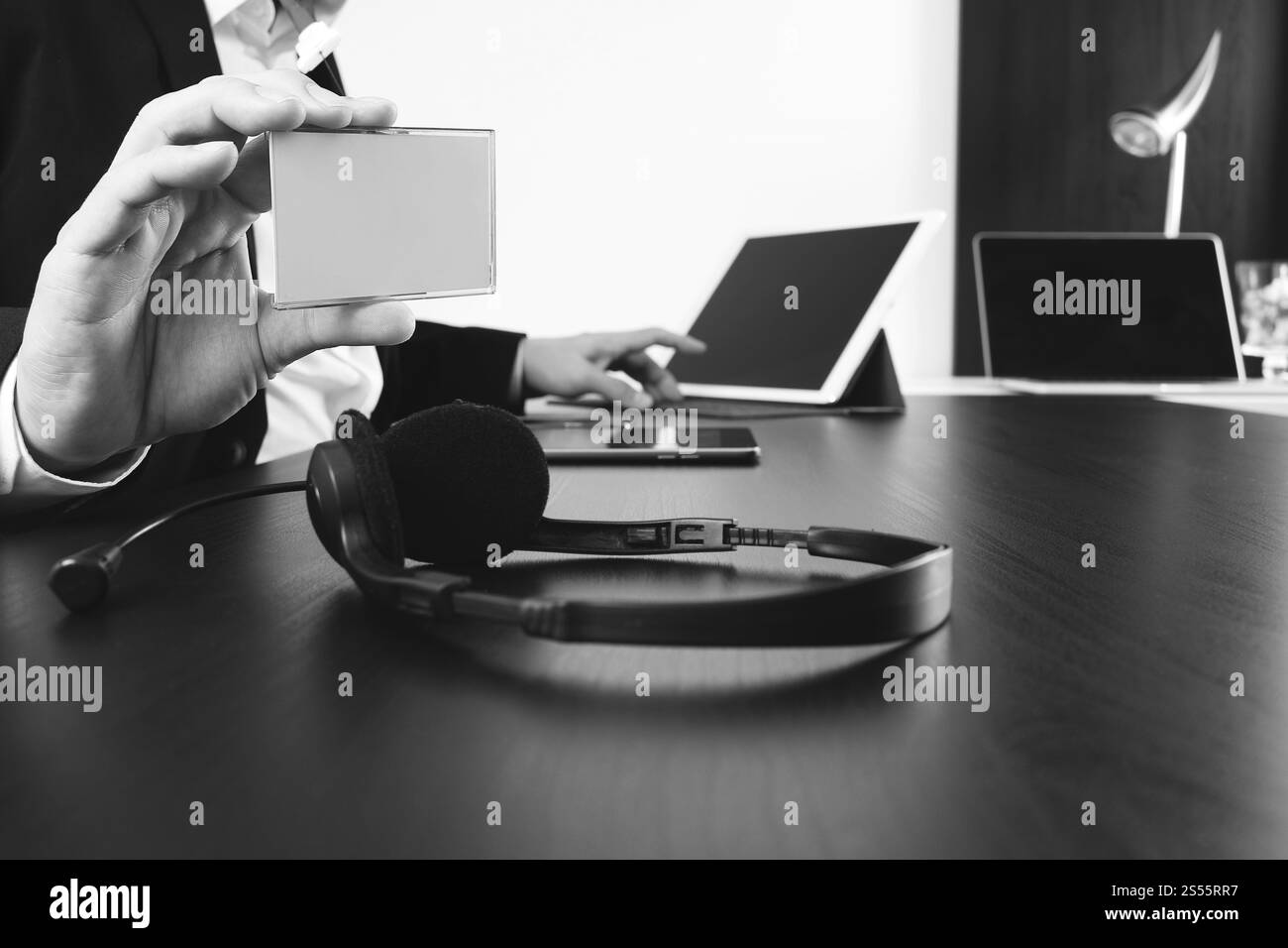 Homme utilisant le casque VoIP et montrer l'étiquette d'identification avec la tablette numérique et l'ordinateur portable comme communication conceptuelle, support informatique, centre d'appels et aide de service Banque D'Images