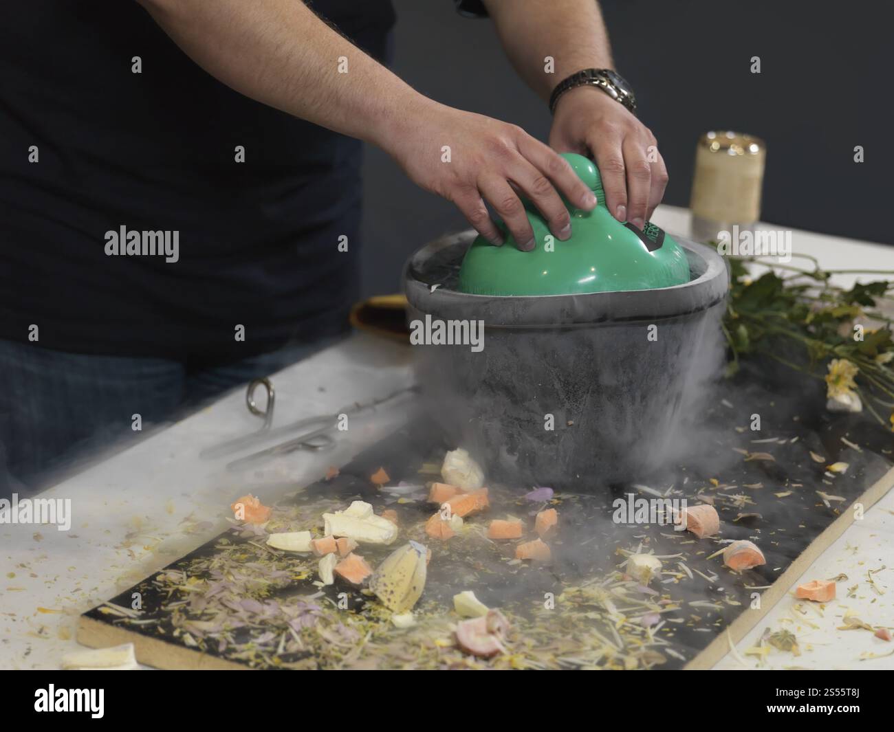 Personne immergeant un ballon à air dans un récipient contenant de l'azote liquide, démontrant la façon dont le gaz à l'intérieur du ballon rétrécit en volume Banque D'Images