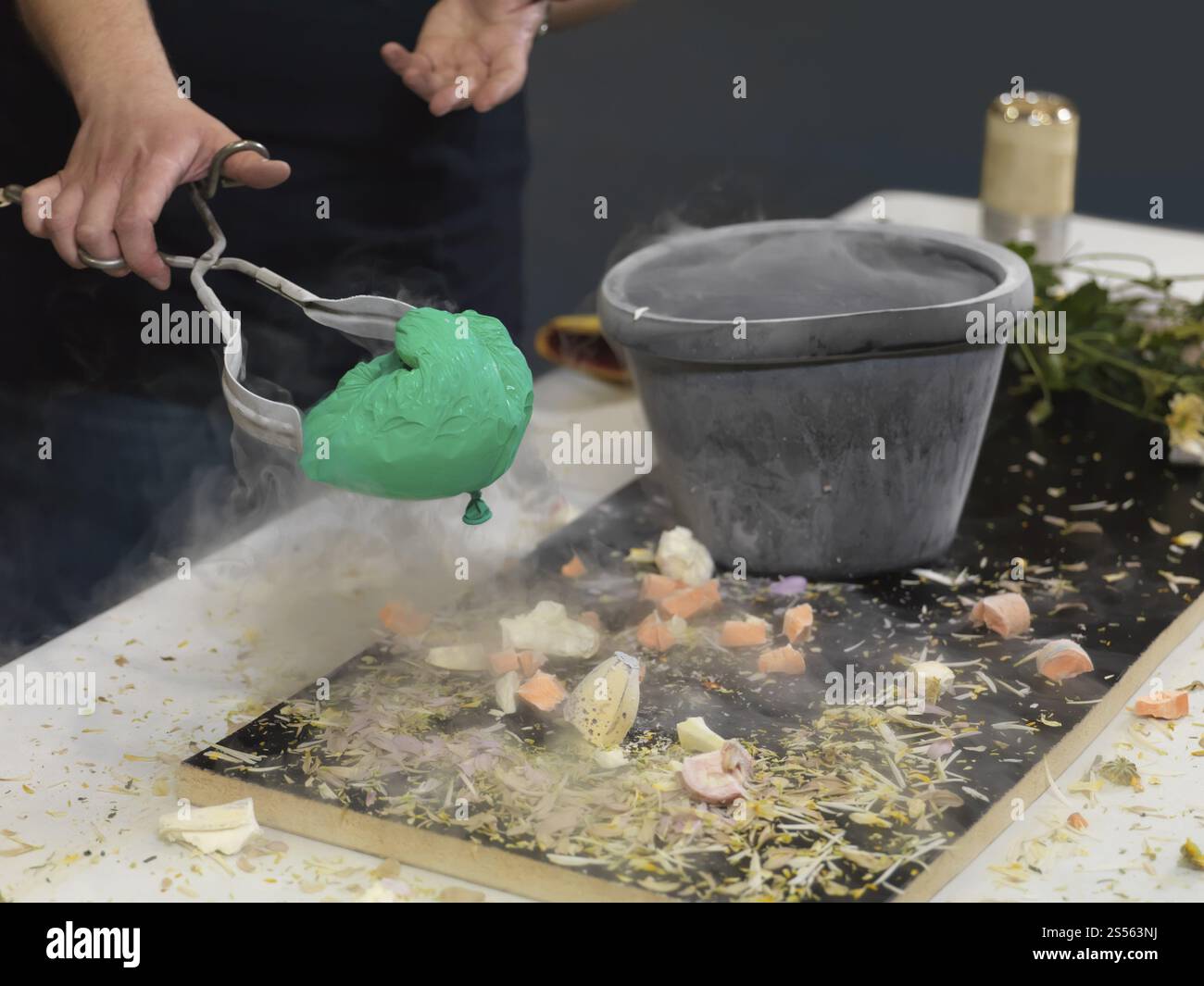 Personne prenant un ballon à air rétréci hors d'un conteneur avec de l'azote liquide, démontrant la façon dont le gaz à l'intérieur du ballon rétrécit en volume Banque D'Images