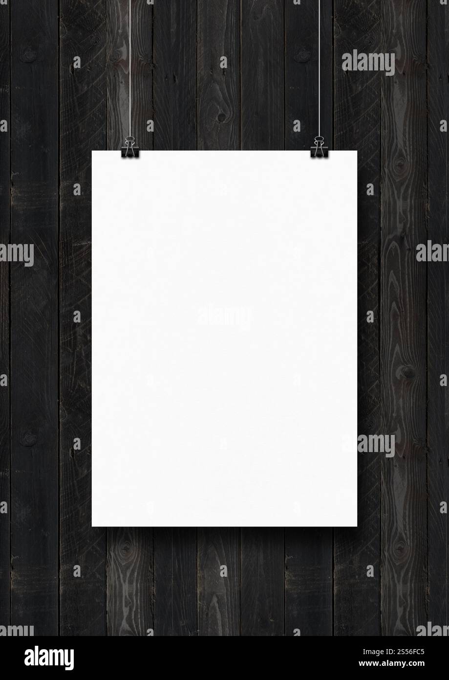 Affiche blanche accrochée sur un mur en bois noir avec des clips. Modèle de maquette vierge. Affiche blanche accrochée sur un mur en bois noir avec des clips Banque D'Images