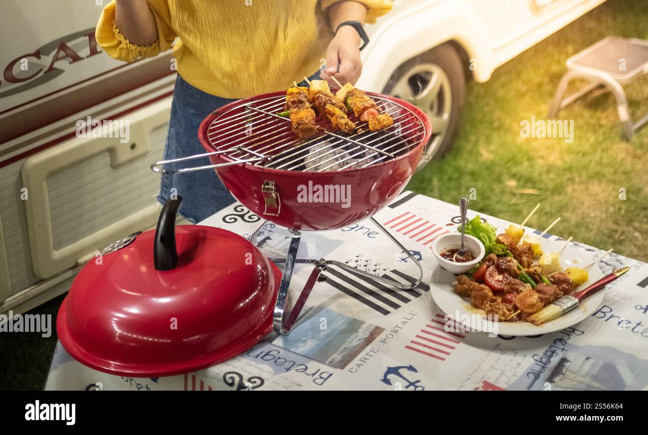 Amis faire barbecue barbecue griller sur un feu chaud dans la nature. Dîner le soir Banque D'Images Amis faire barbecue barbecue griller sur un feu chaud dans la nature. Dîner le soir Banque D'Images
