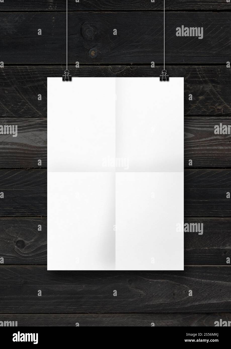 Affiche pliée blanche accrochée sur un mur en bois noir avec des clips. Modèle de maquette vierge. Affiche pliée blanche accrochée sur un mur en bois noir avec des clips Banque D'Images