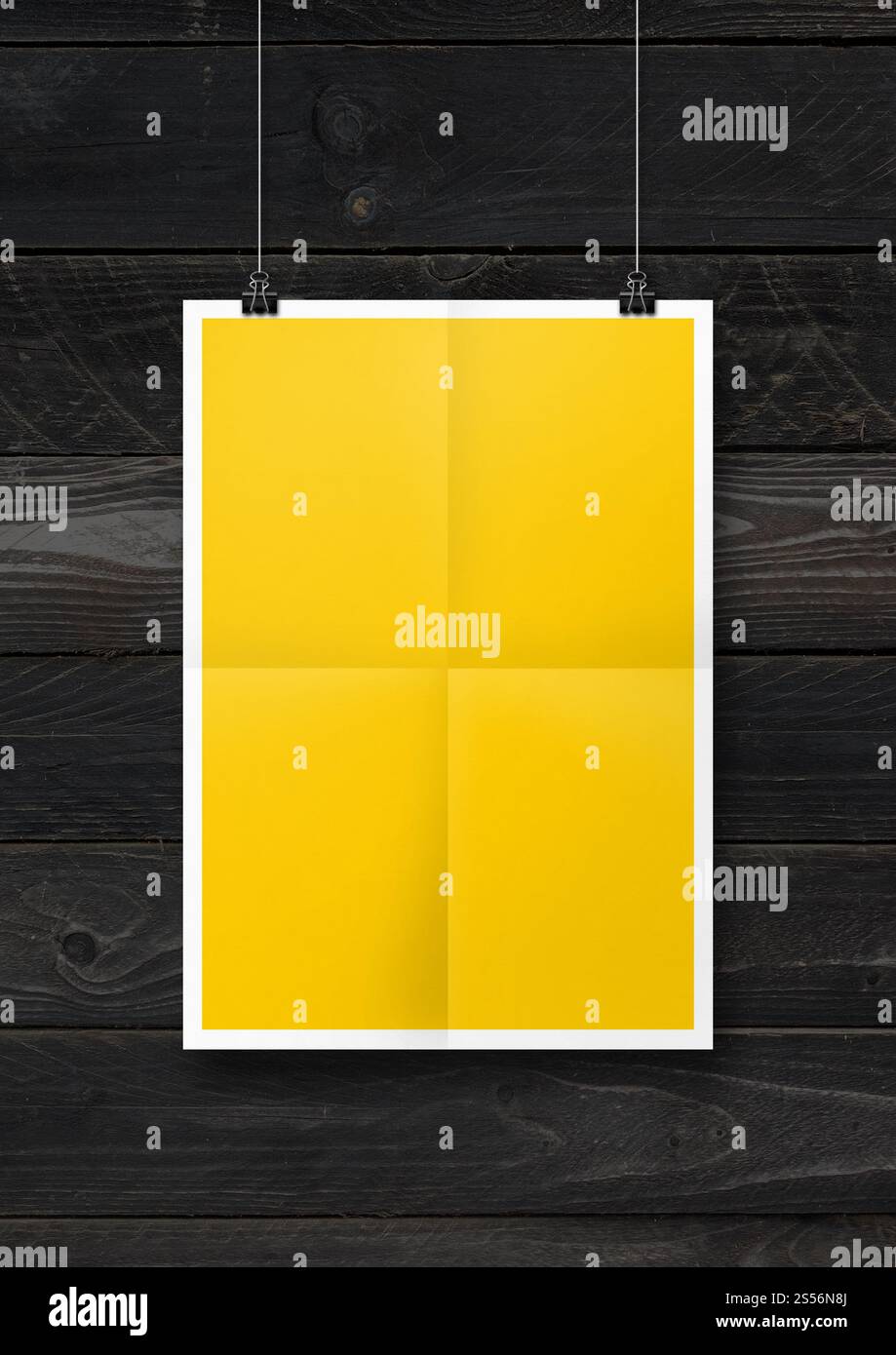 Affiche pliée jaune accrochée sur un mur en bois noir avec des clips. Modèle de maquette vierge. Affiche pliée jaune accrochée sur un mur en bois noir avec des clips Banque D'Images