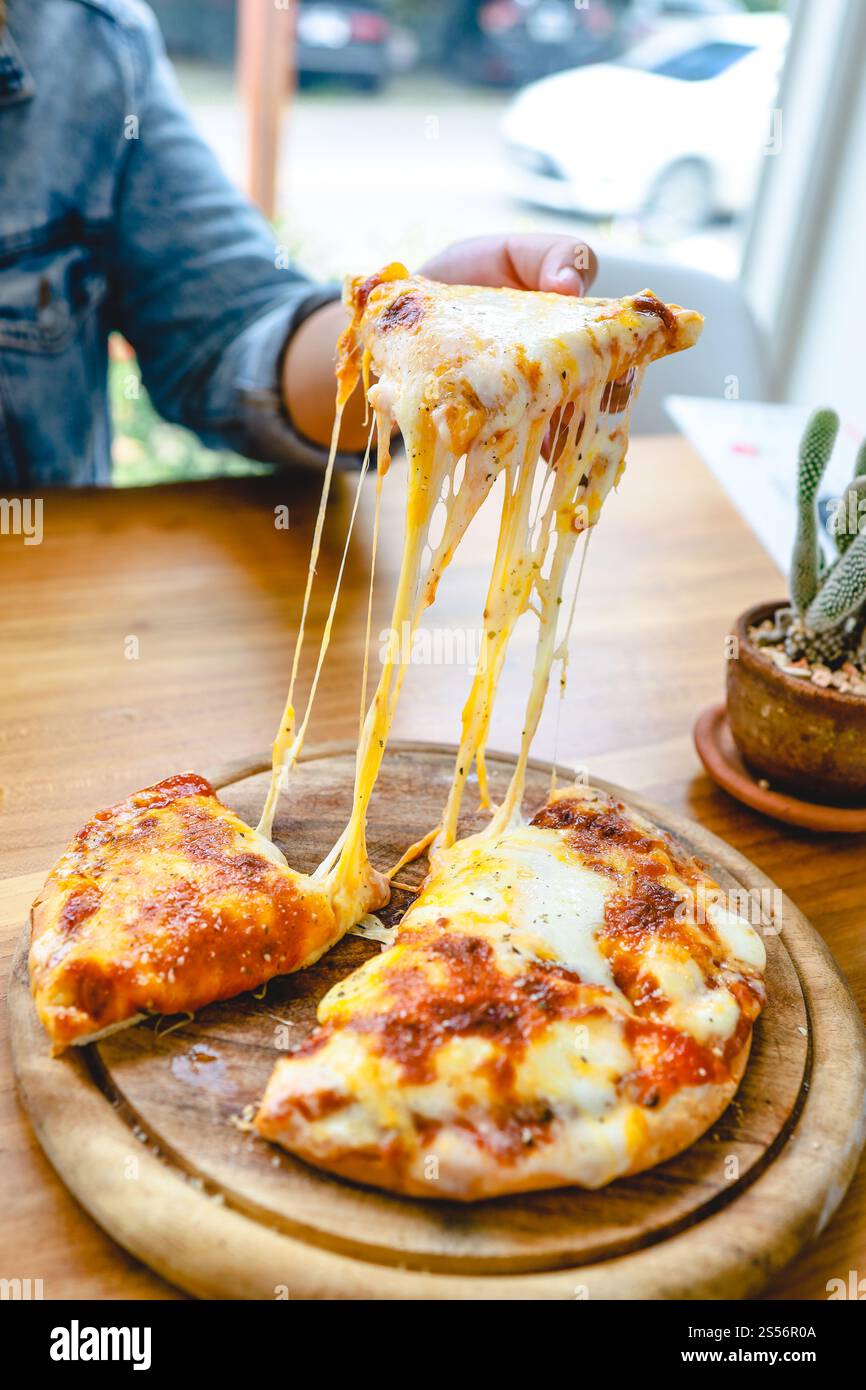 Une tranche de fromage mozzarella pizza végétarienne fraîche chaude très fromagère. Fromage fondant italien Pizza Margherita à la main Banque D'Images