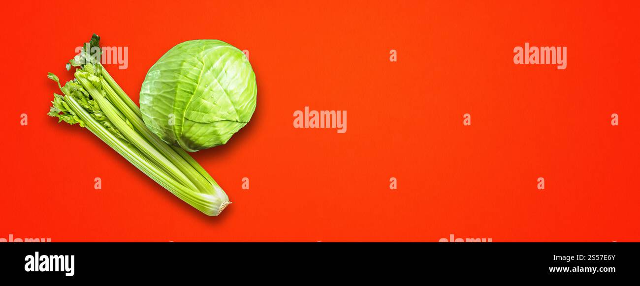 Bouquet de branches de céleri et chou vert isolé sur fond de bannière rouge. Vue de dessus. Bouquet de branches de céleri et chou vert isolé sur la bannière rouge Banque D'Images