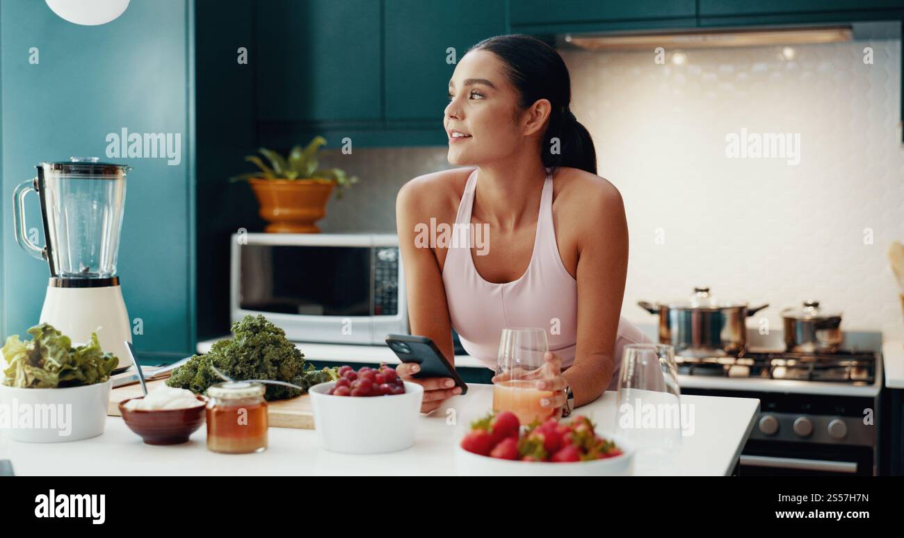 Téléphone portable, pensée et femme avec smoothie dans la cuisine pour la santé, le bien-être et le petit déjeuner diététique. Heureux, idée et personne féminine avec téléphone pour la nutrition Banque D'Images
