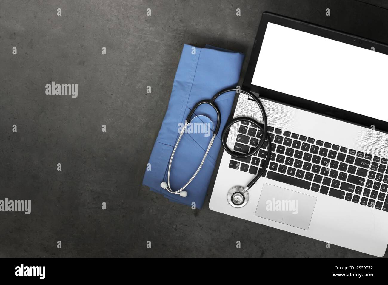 vue de dessus de l'espace de travail de médical avec stéthoscope et manteau bleu et ordinateur portable d'écran blanc sur fond de bureau de texture Banque D'Images