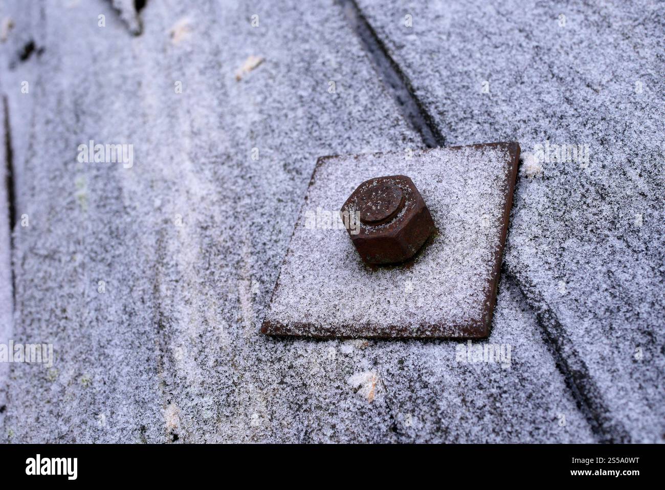 Écrou et boulon sur une plaque métallique carrée givrée sur un tambour de câble. Banque D'Images