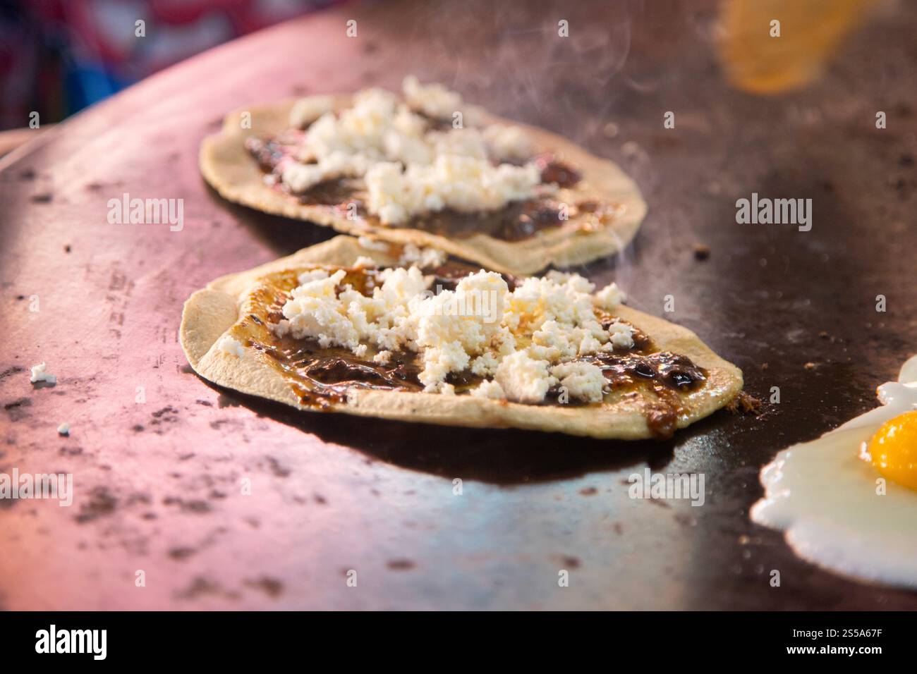 Cuisson de memelas au marché d'Oaxaca Central de Abastos avec fromage local, porc séché, œufs et sauce piquante. Banque D'Images