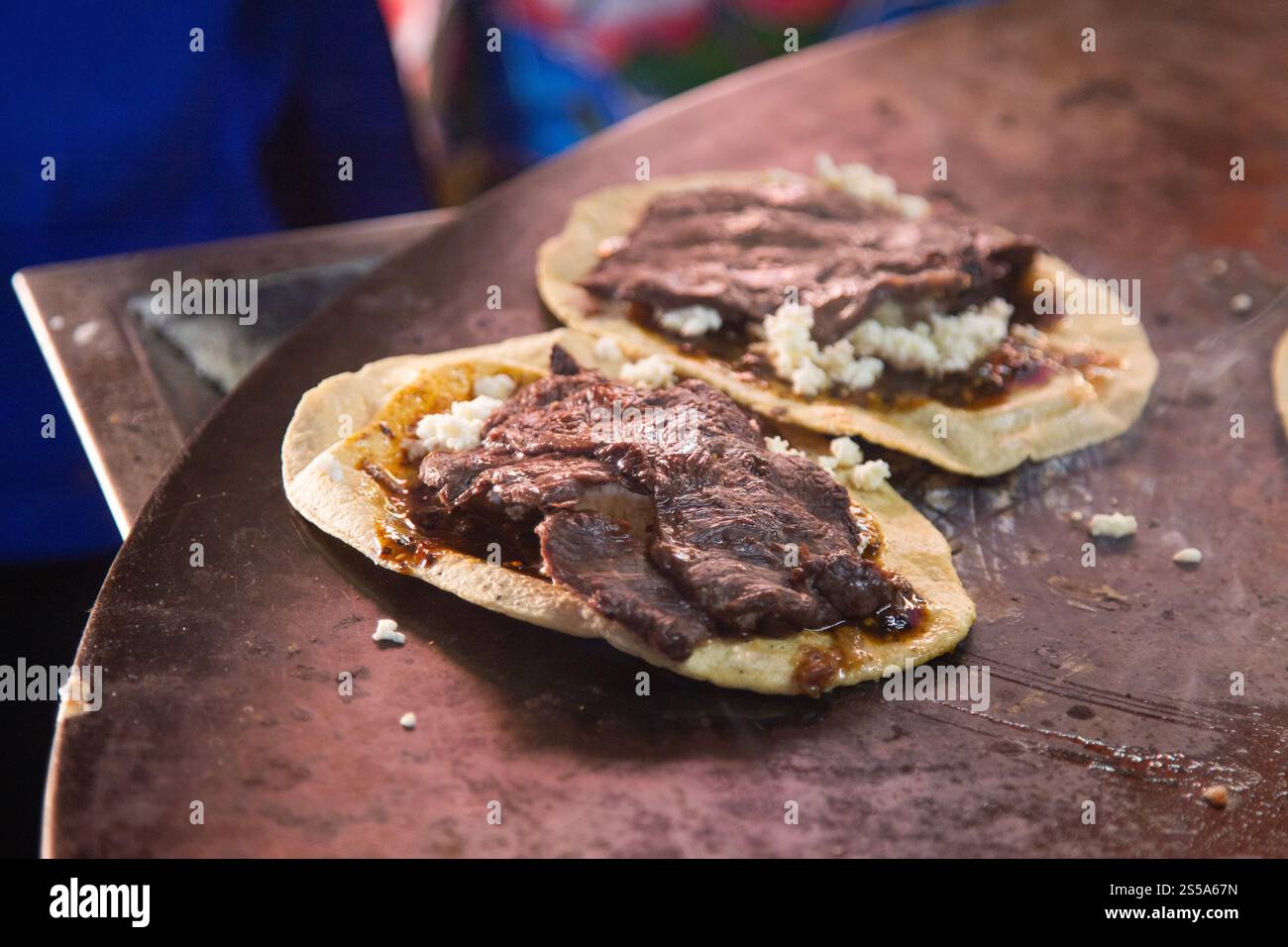 Cuisson de memelas au marché d'Oaxaca Central de Abastos avec fromage local, porc séché, œufs et sauce piquante. Banque D'Images
