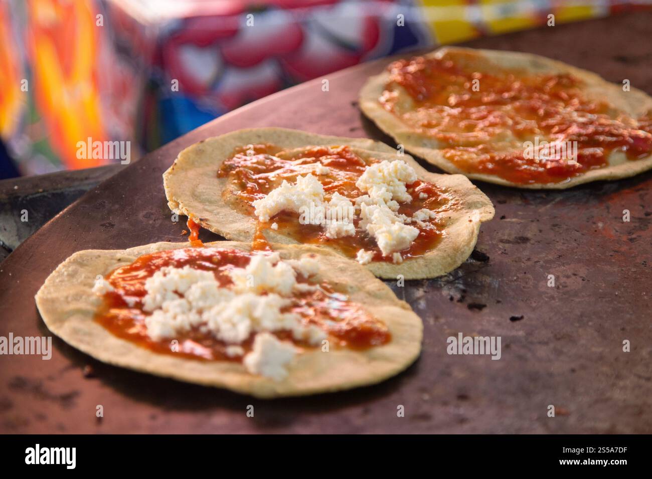 Cuisson de memelas au marché d'Oaxaca Central de Abastos avec fromage local, porc séché, œufs et sauce piquante. Banque D'Images