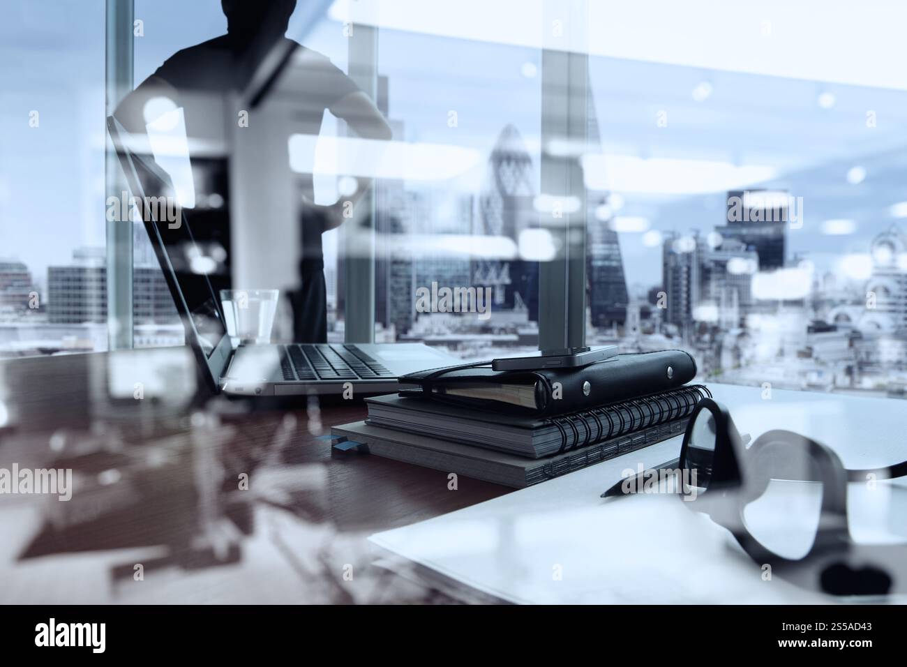 double exposition de documents d'affaires sur la table de bureau avec téléphone intelligent et tablette numérique et londres ville floue la vue et l'homme pensant dans le Banque D'Images