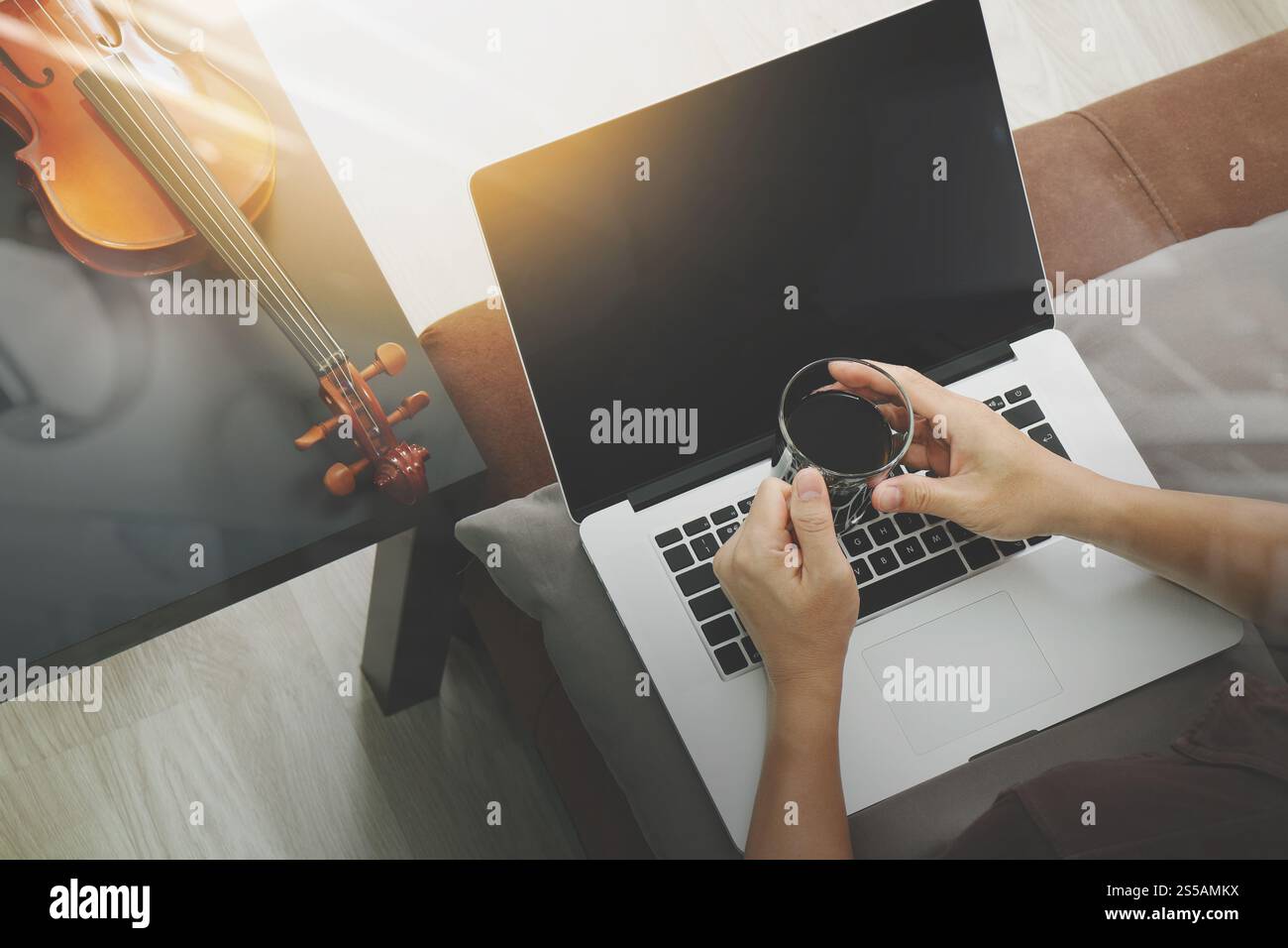 Hipster part composer de la musique avec ordinateur portable compter et tenant une tasse de café et sitting on sofa at home studio Banque D'Images