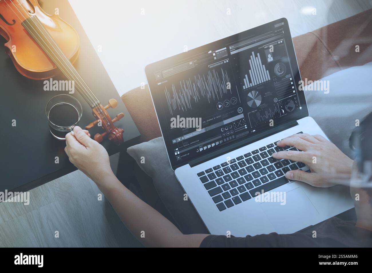 Hipster part composer de la musique avec ordinateur portable compter et sitting on sofa at home studio Banque D'Images