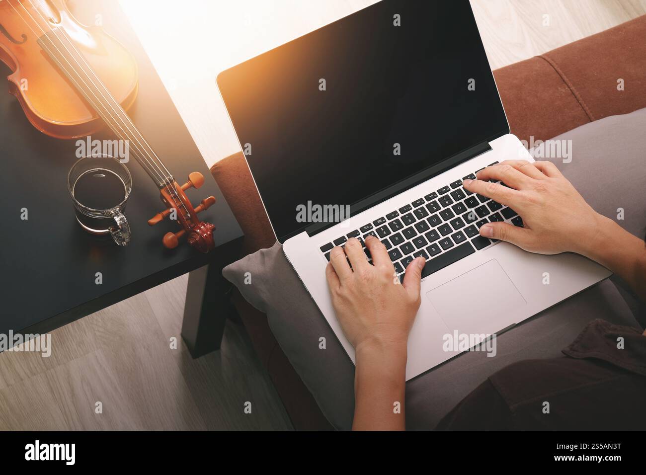 Hipster part composer de la musique avec ordinateur portable compter et sitting on sofa at home studio Banque D'Images