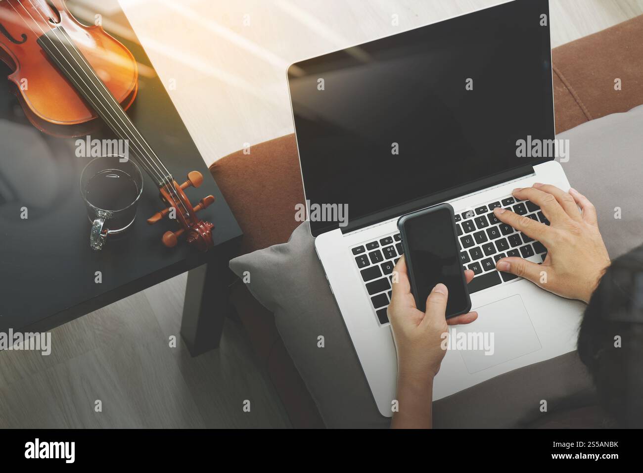 Hipster part composer la musique avec smart phone compter et sitting on sofa at home studio Banque D'Images