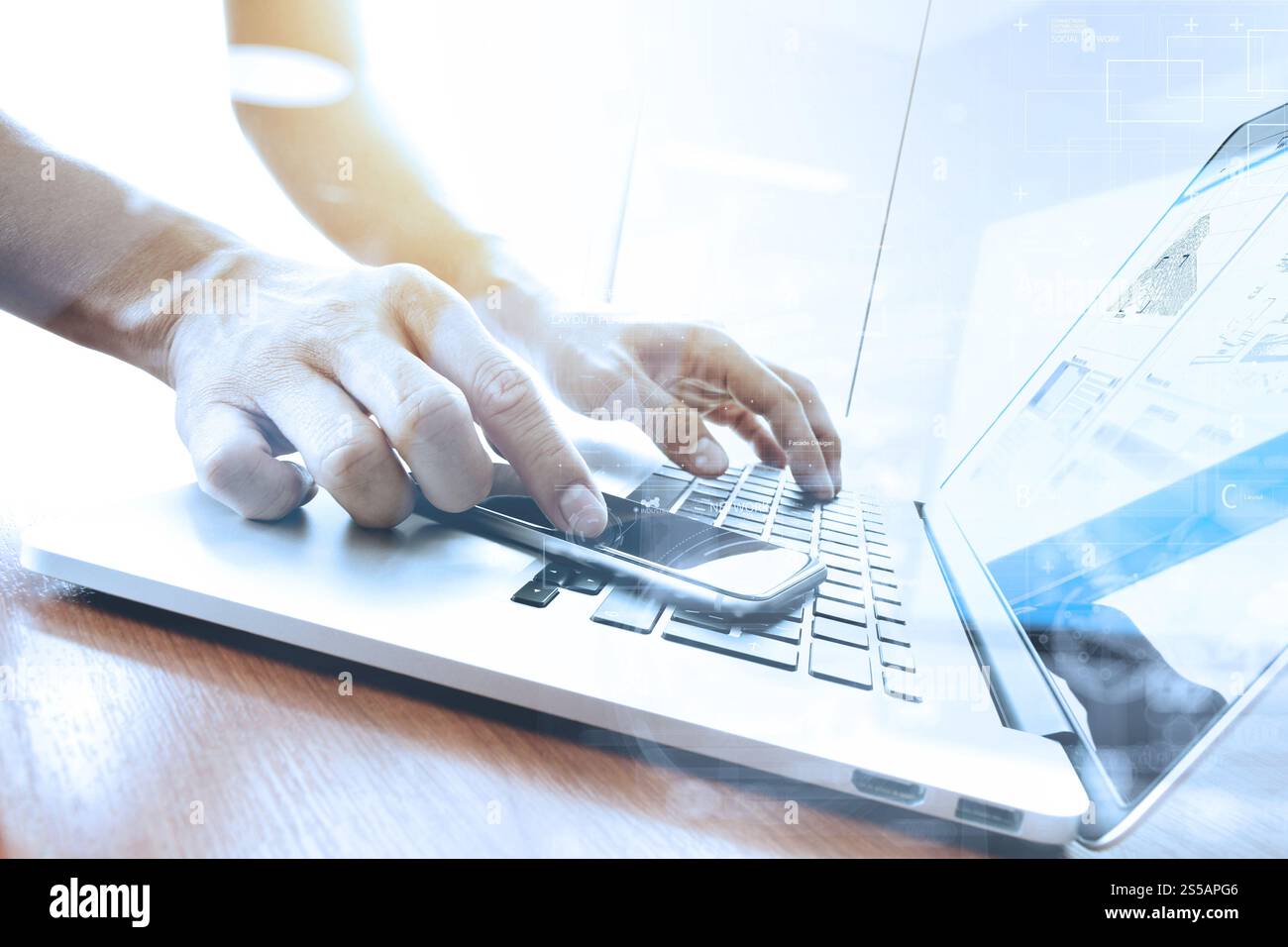 Main designer travaillant et smart phone et l'ordinateur portable sur un bureau en bois Banque D'Images