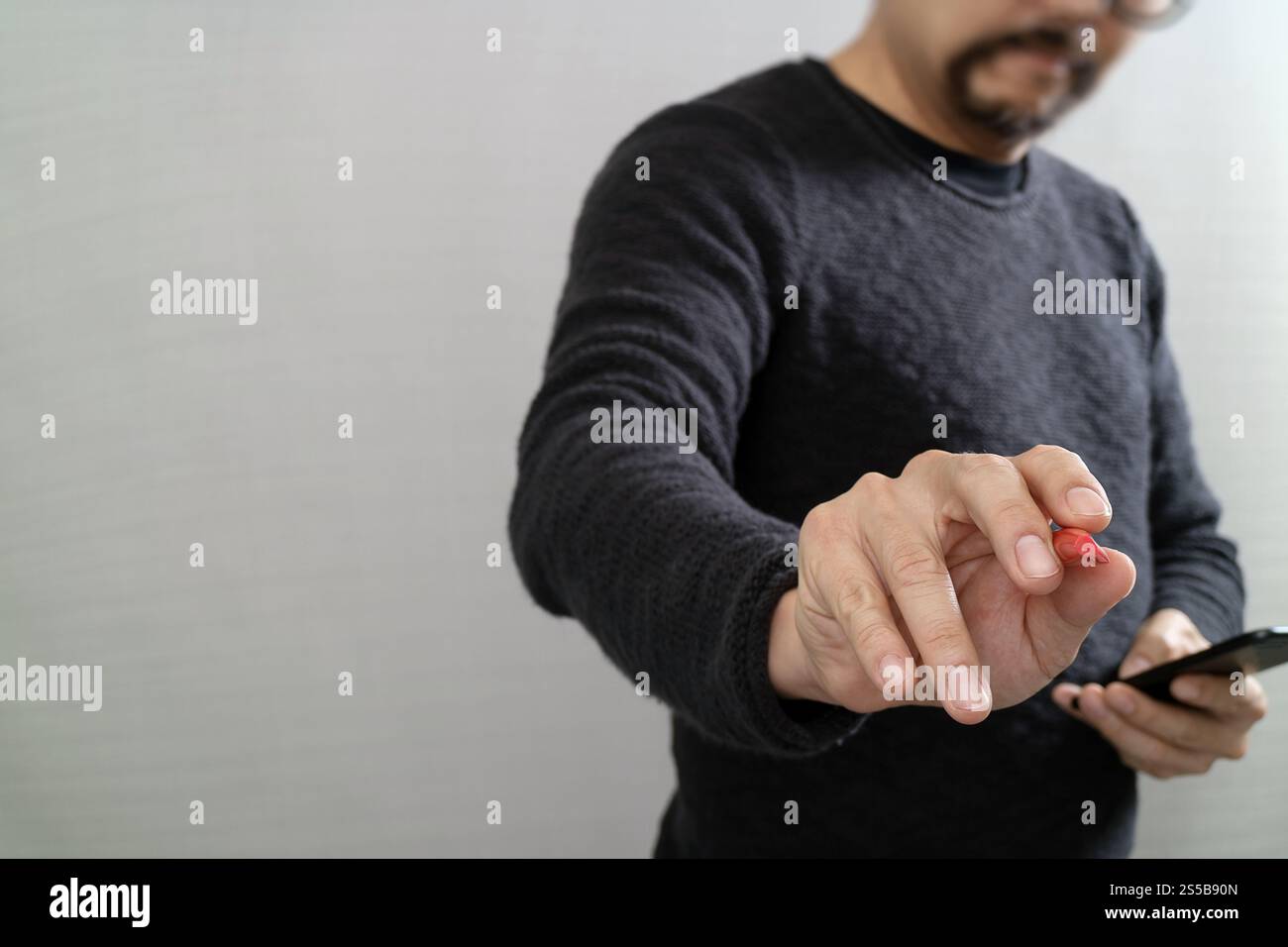 Main d'homme d'affaires avec stylo appuyant sur un bouton imaginaire, tenant le téléphone intelligent, icônes virtuelles graphiques d'écran numérique, graphique, diagramme Banque D'Images