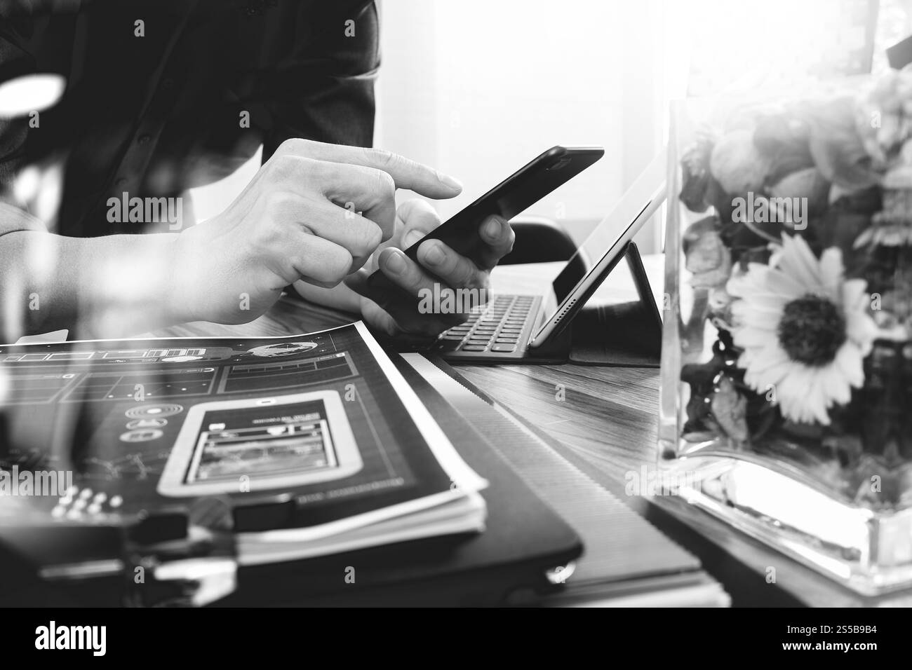Businessman hand en utilisant les paiements mobiles,vente en ligne omni channel,ordinateur portable sur un bureau en bois,fleurs,vase en verre noir et blanc Banque D'Images