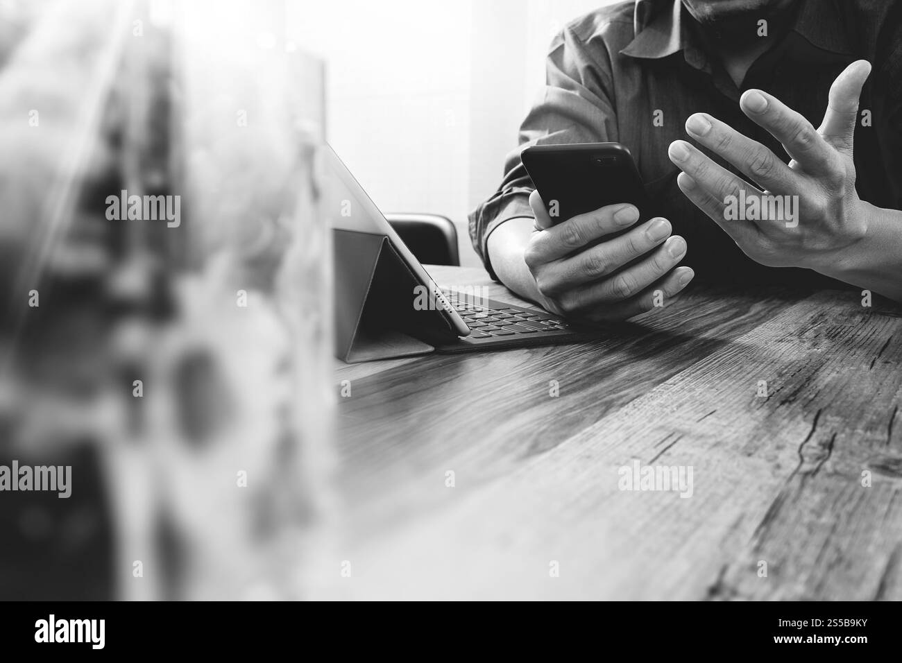main d'homme d'affaires utilisant le téléphone intelligent, paiements mobiles achats en ligne, omni canal, ordinateur de clavier d'amarrage de tablette numérique, vase en verre de fleur sur bois Banque D'Images