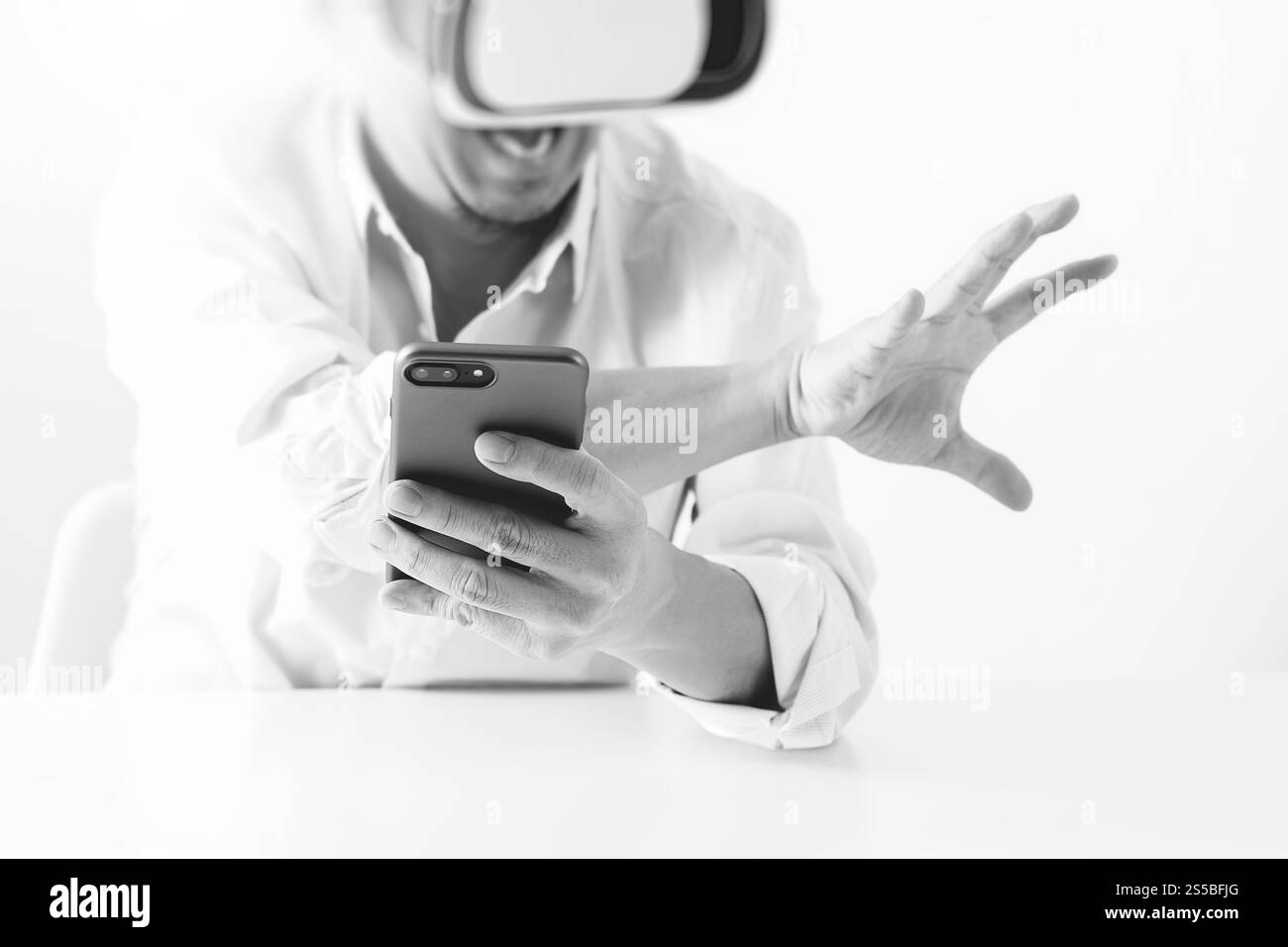 Businessman wearing lunettes de réalité virtuelle dans un bureau moderne avec l'aide du Smartphone avec casque VR noir et blanc Banque D'Images