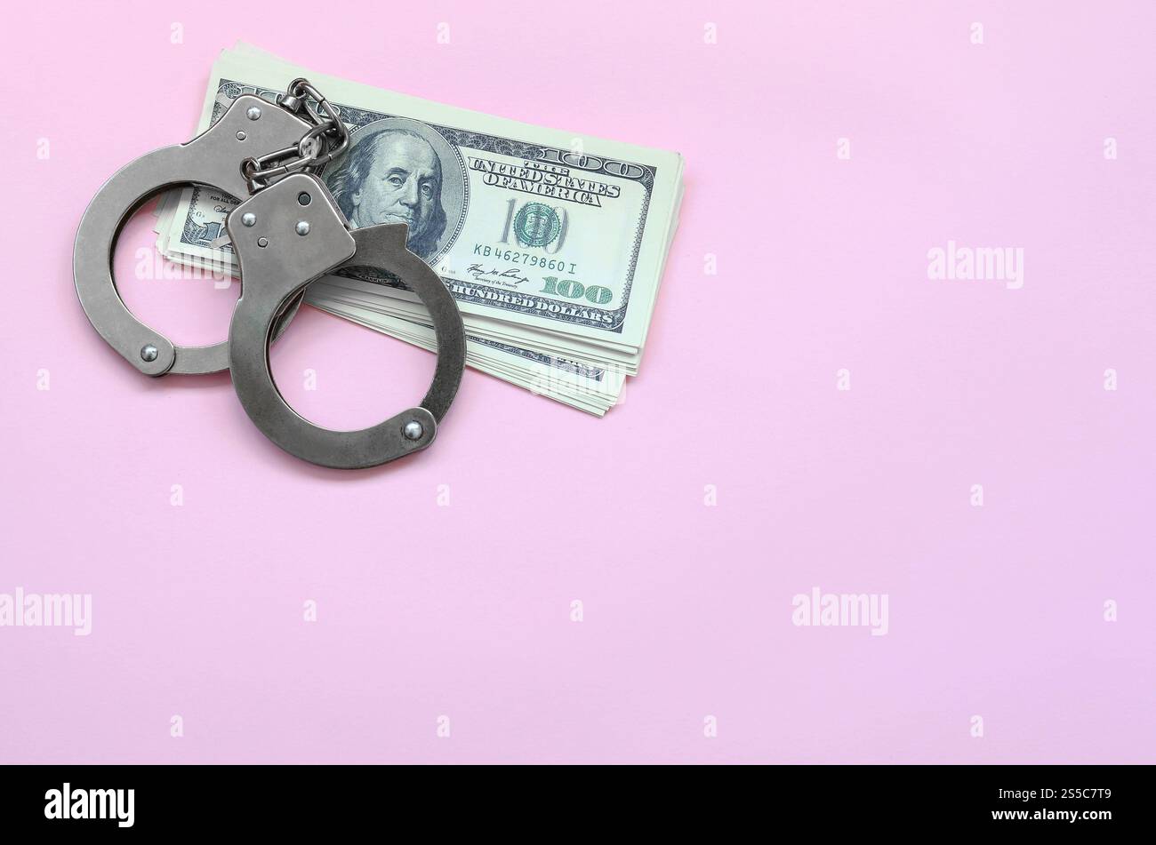 Les menottes de la police et des centaines de dollars américains reposent sur un fond de couleur corail vivant. Le concept de sanction pour violation de la loi dans le domaine financier Banque D'Images