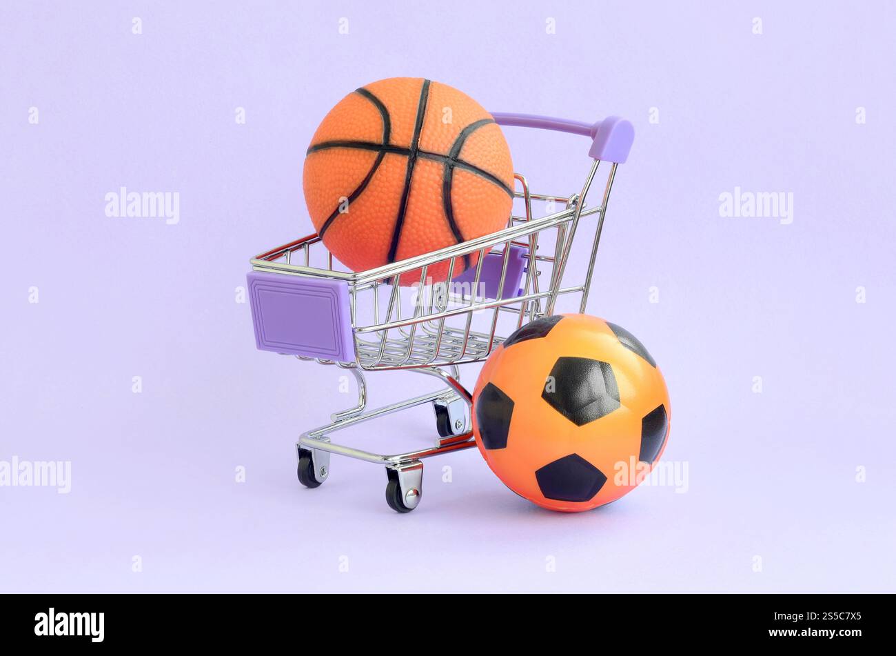 Basket-ball orange et ballon de football dans le panier sur violet. Le concept de vente d'équipements sportifs, les prévisions pour les matchs sportifs, les sports Banque D'Images