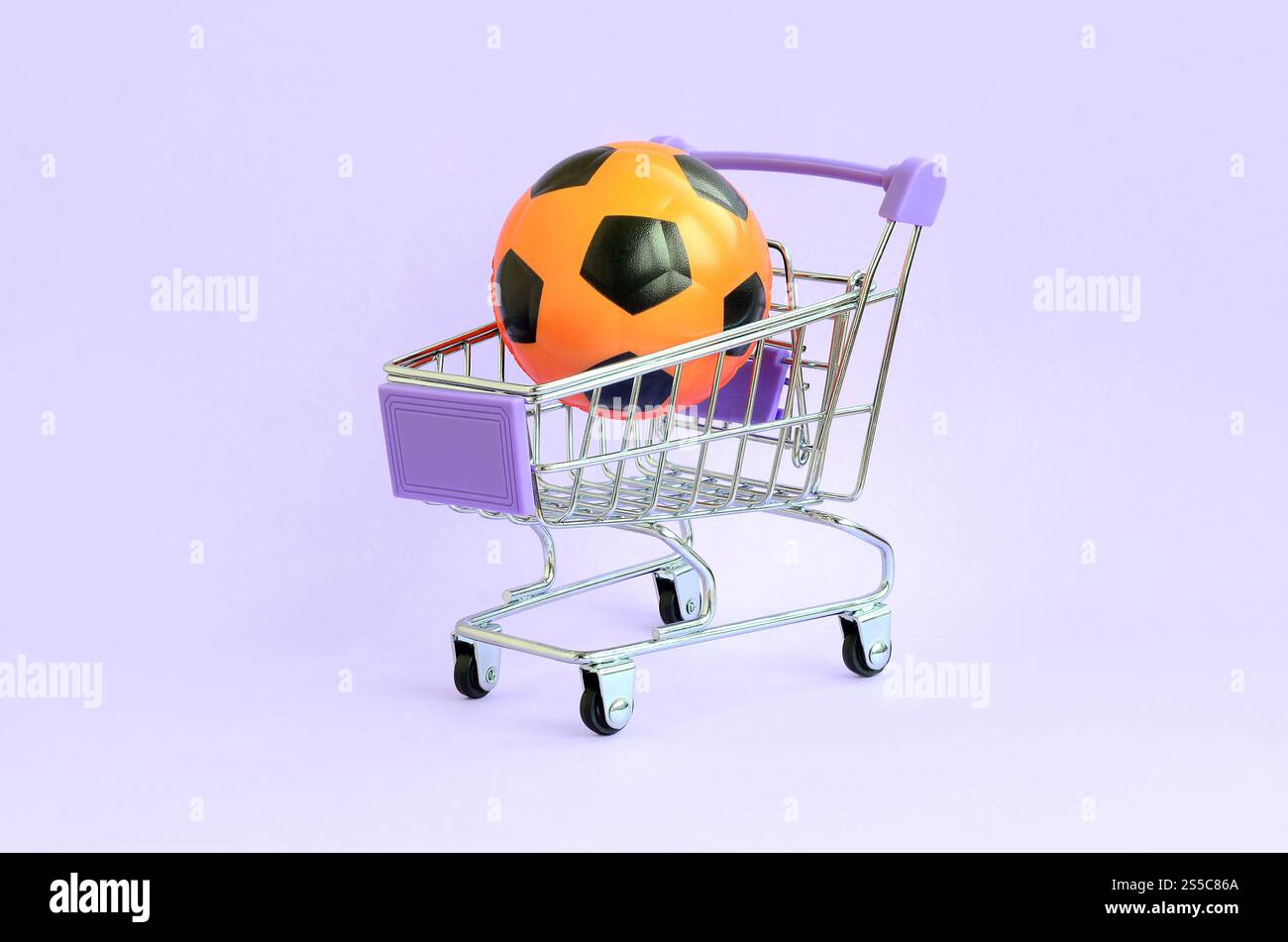 Ballon de football orange dans un panier sur violet. Le concept de vente d'équipements sportifs, les prévisions pour les matchs sportifs, les Paris sportifs. Vente Banque D'Images