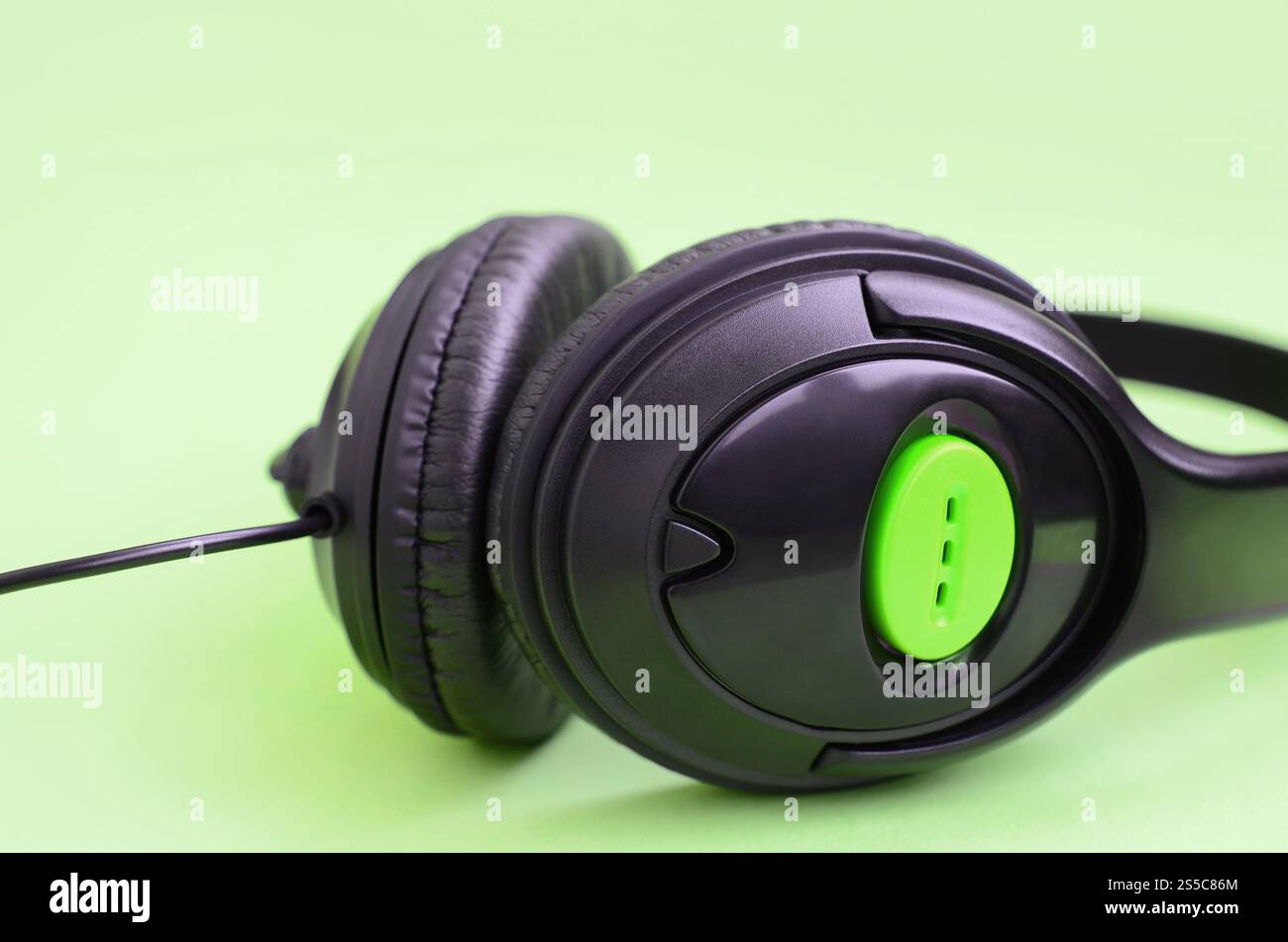 Casque noir repose sur un fond vert pastel coloré. Concept d'écoute de musique. Concept d'écoute de musique. Casque noir repose sur le vert Banque D'Images