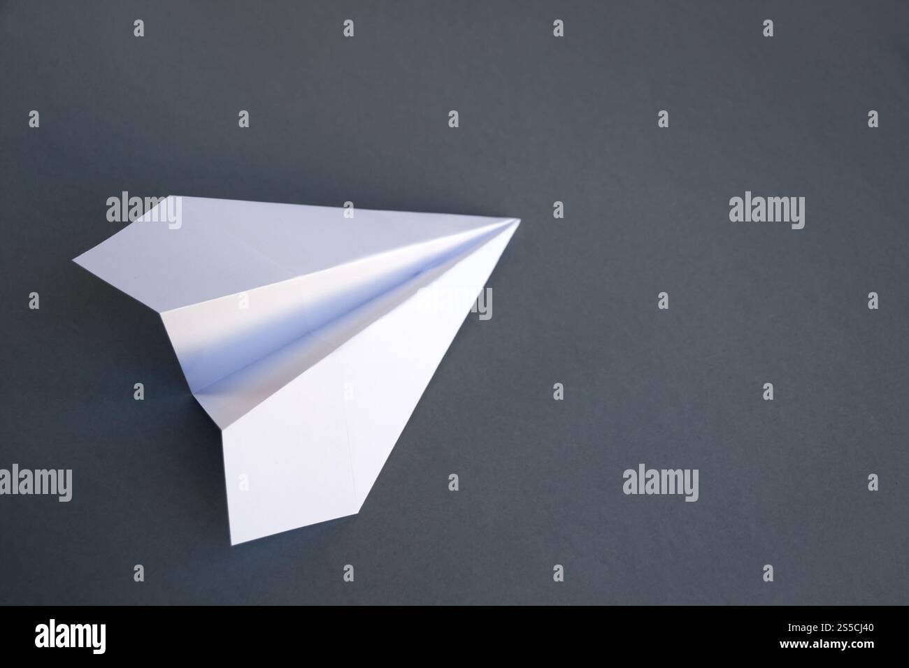 Origami avion en papier blanc isolé sur un fond gris vierge. Origami avion en papier blanc isolé sur un fond gris Banque D'Images