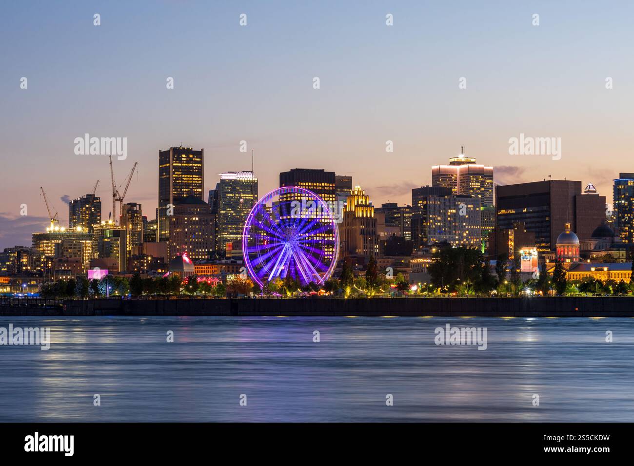 Vieux-Port de Montréal et horizon du centre-ville la nuit. Les lumières colorées des bâtiments se reflètent dans l'eau. Montréal, Québec, Canada. Grande roue. Banque D'Images