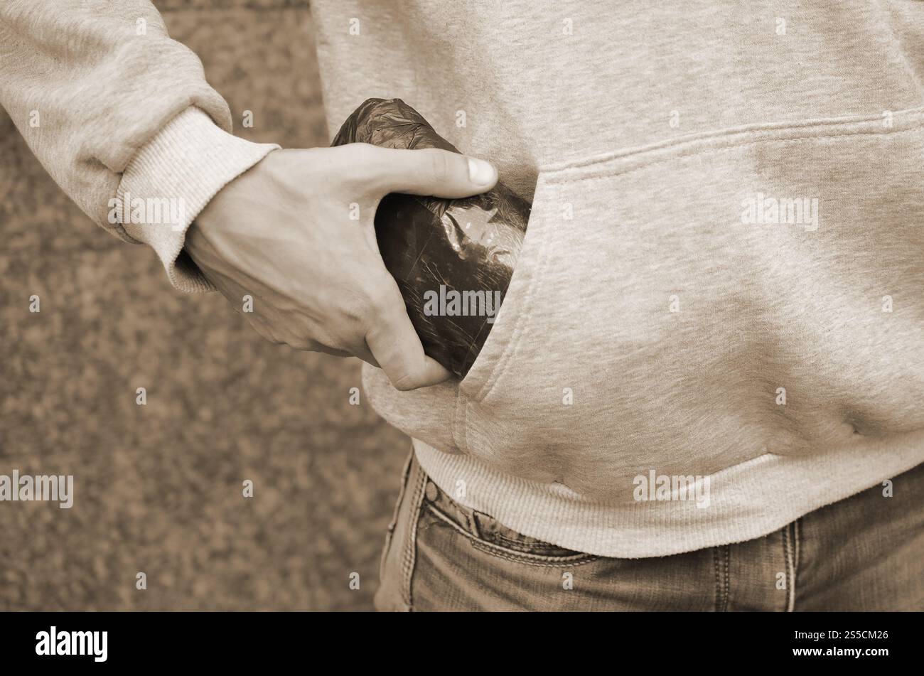 Trafiquant de drogue prenant sac avec de la cocaïne hors de la poche du sweat à capuche sur fond de tuiles sombres en gros plan. Concept de trafic de stupéfiants. Toxicomanie. Trafiquant de drogue Banque D'Images