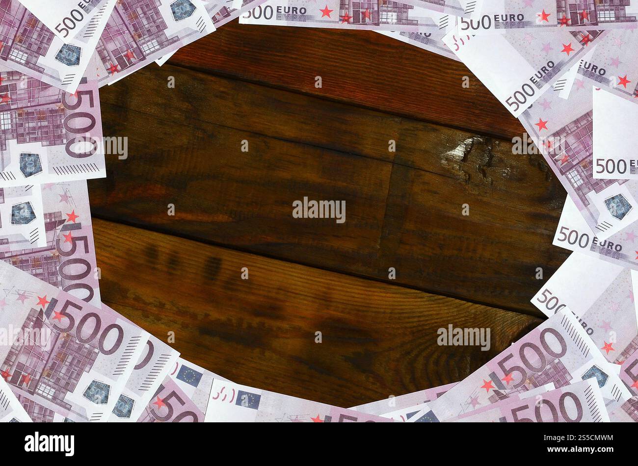 Beaucoup de dénominations pourpres d'une valeur de 500 euros se trouvent sur une surface en bois avec un bloc vide au milieu de l'image. Copier l'espace pour le texte Banque D'Images
