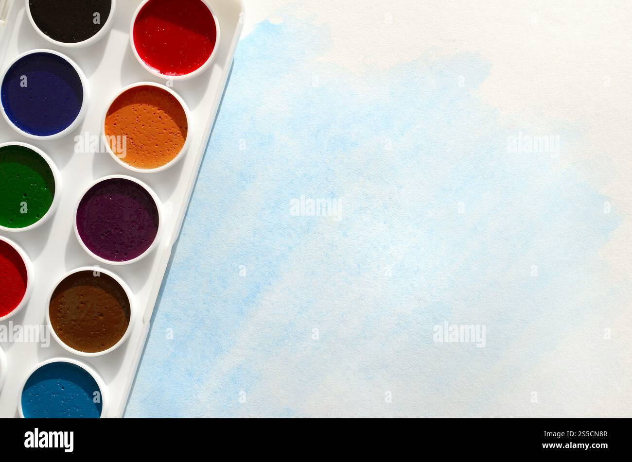 Un nouvel ensemble d'aquarelles repose sur une feuille de papier, qui montre un dessin abstrait d'aquarelle sous la forme de traits bleus. Le concept d'amateur Banque D'Images
