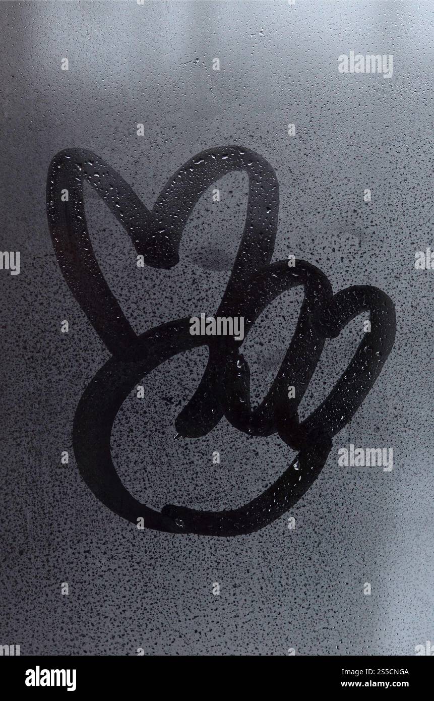L'image du symbole de paix est dessinée avec un doigt sur la surface d'une fenêtre en verre embué. Combinaison de deux doigts Banque D'Images