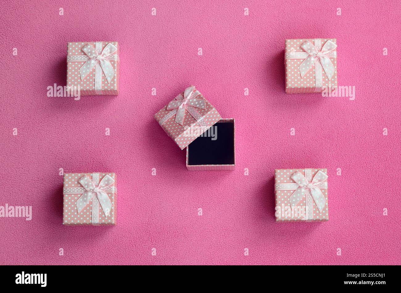Beaucoup de petits coffrets cadeaux de couleur rose avec un petit noeud repose sur une couverture de tissu polaire rose clair doux et fourré. Emballage pour un cadeau à votre charmante Banque D'Images