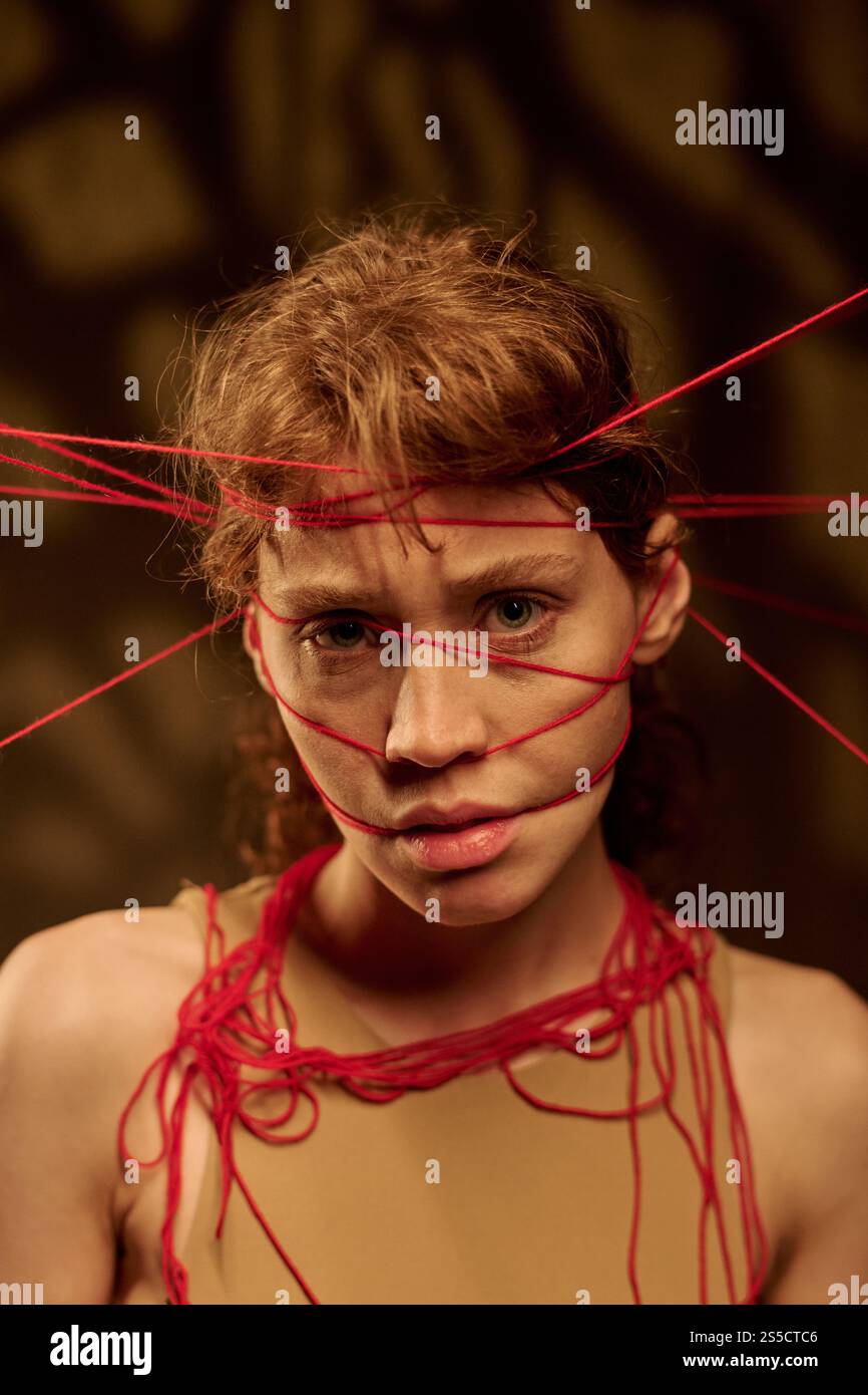 Portrait vertical d'une jeune femme adulte regardant la caméra agressivement, elle portant une couronne faite de fils Banque D'Images