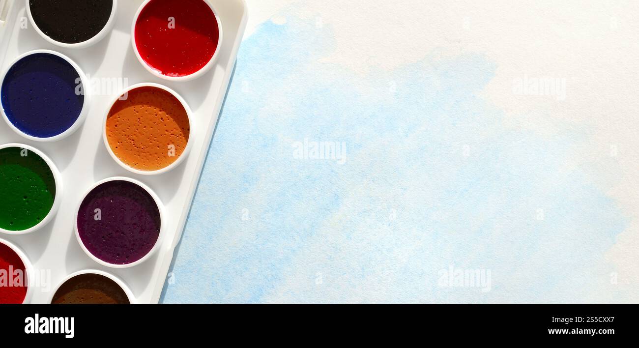 Un nouvel ensemble d'aquarelles repose sur une feuille de papier, qui montre un dessin abstrait d'aquarelle sous la forme de traits bleus. Le concept d'amateur Banque D'Images