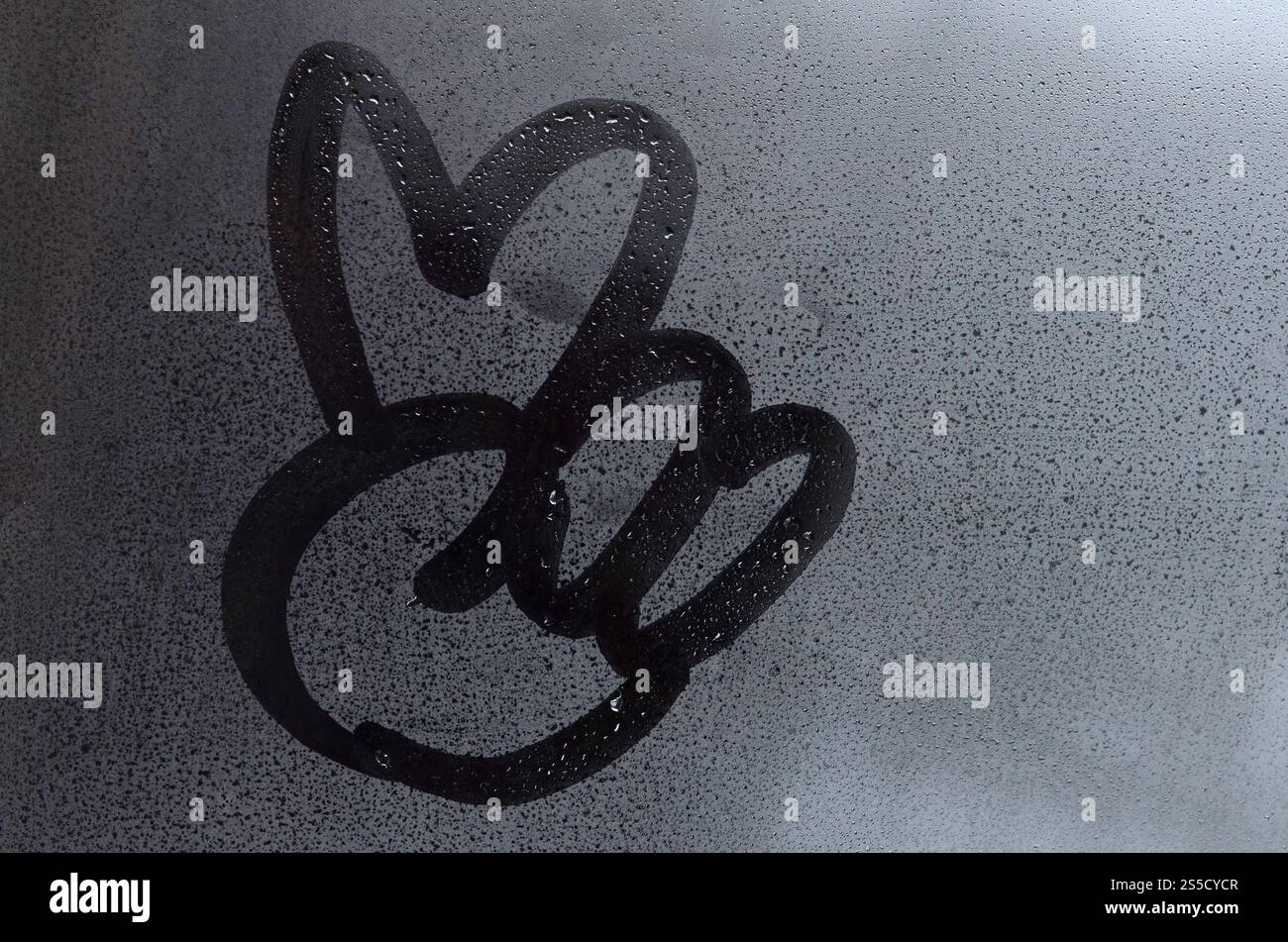 L'image du symbole de paix est dessinée avec un doigt sur la surface d'une fenêtre en verre embué. Combinaison de deux doigts Banque D'Images