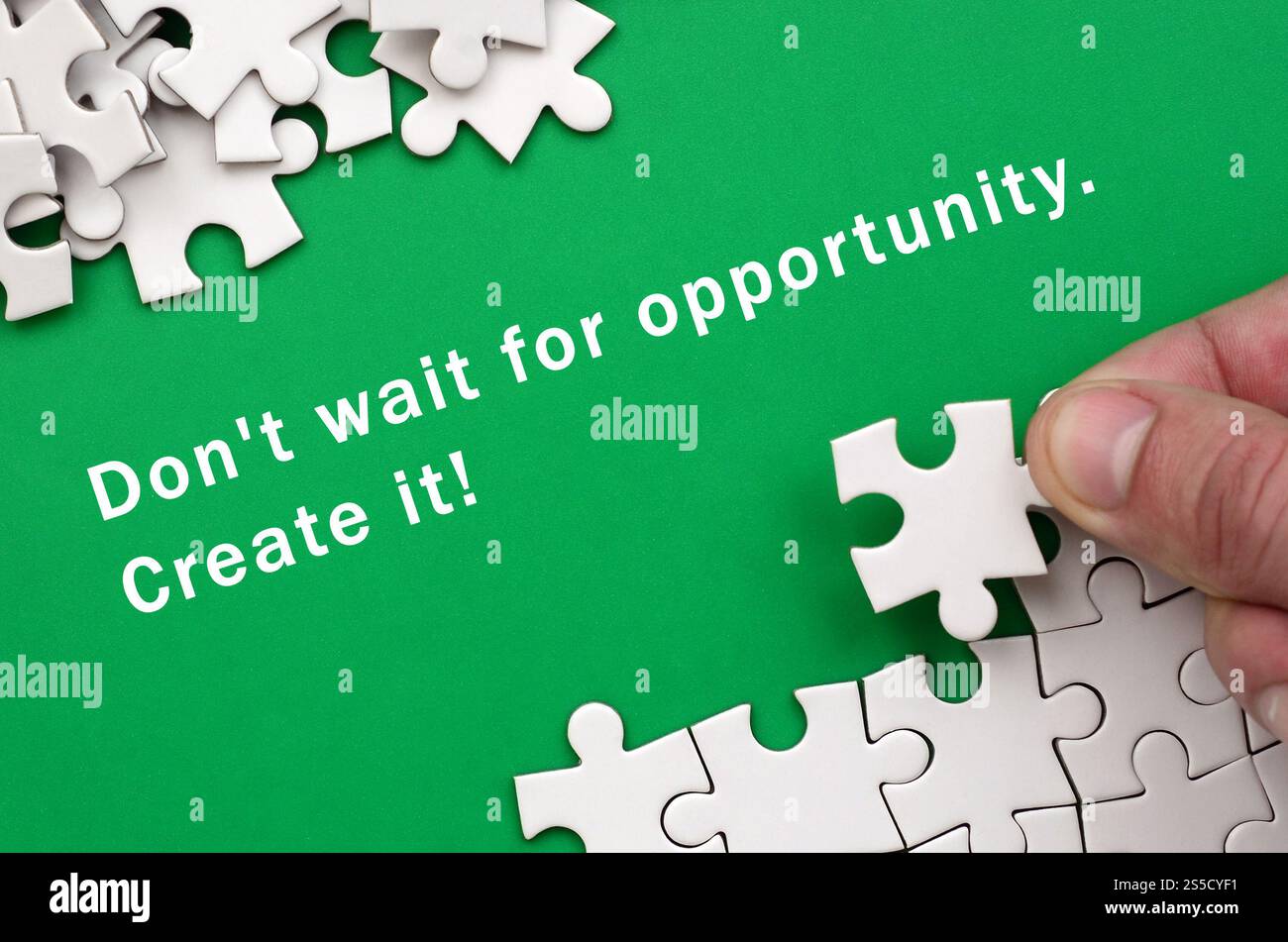N'attendez pas l'occasion. Créez-le. La main plie un puzzle blanc et une pile de pièces de puzzle non peignées se trouve sur le fond du Banque D'Images