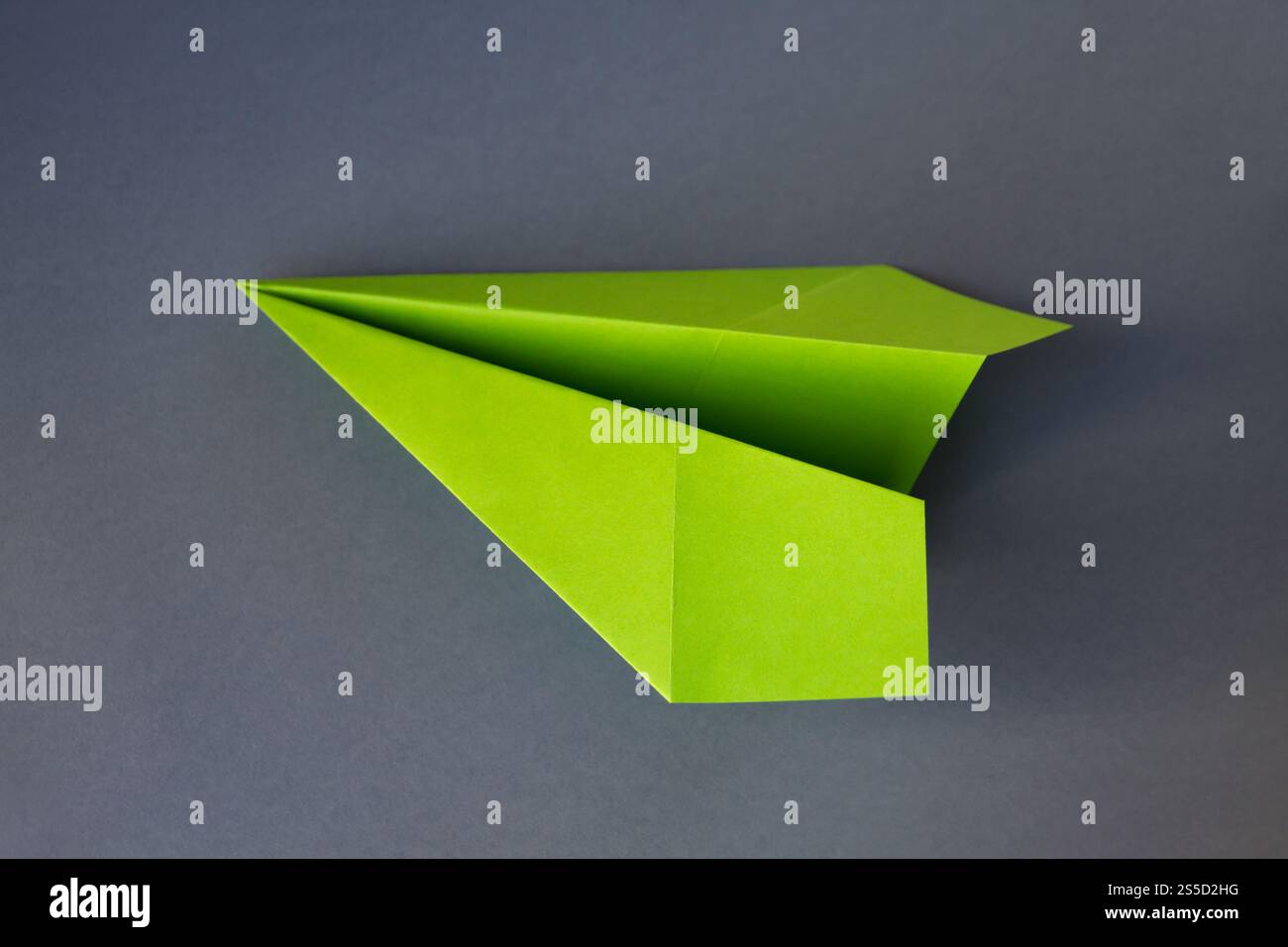 Origami plan en papier vert isolé sur un fond gris vierge. Origami plan en papier vert isolé sur un fond gris Banque D'Images