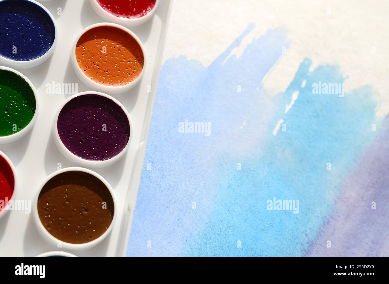 Un nouvel ensemble d'aquarelles repose sur une feuille de papier, qui montre un dessin abstrait d'aquarelle sous la forme de traits bleus. Le concept d'amateur Banque D'Images