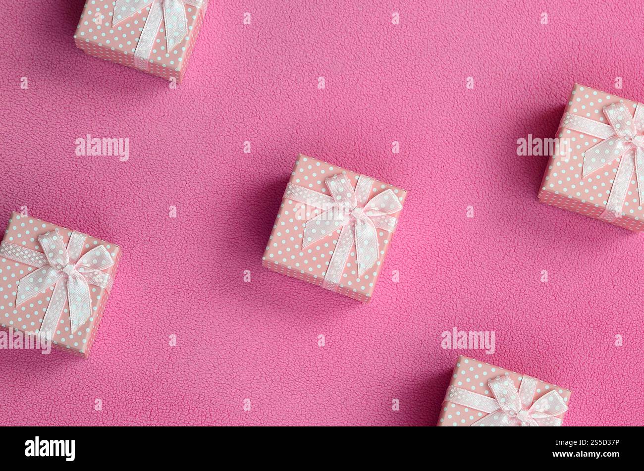 Beaucoup de petits coffrets cadeaux de couleur rose avec un petit noeud repose sur une couverture de tissu polaire rose clair doux et fourré. Emballage pour un cadeau à votre charmante Banque D'Images