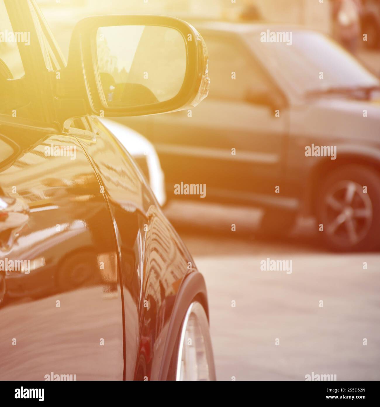 Vue en diagonale d'une voiture noire brillante avec des roues blanches, qui se trouve sur un carré de carreaux gris Banque D'Images