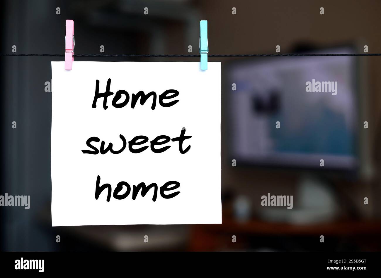 Maison Sweet home. Note est écrit sur un autocollant blanc qui est suspendu avec une pince à linge sur une corde sur un fond d'intérieur de bureau Banque D'Images