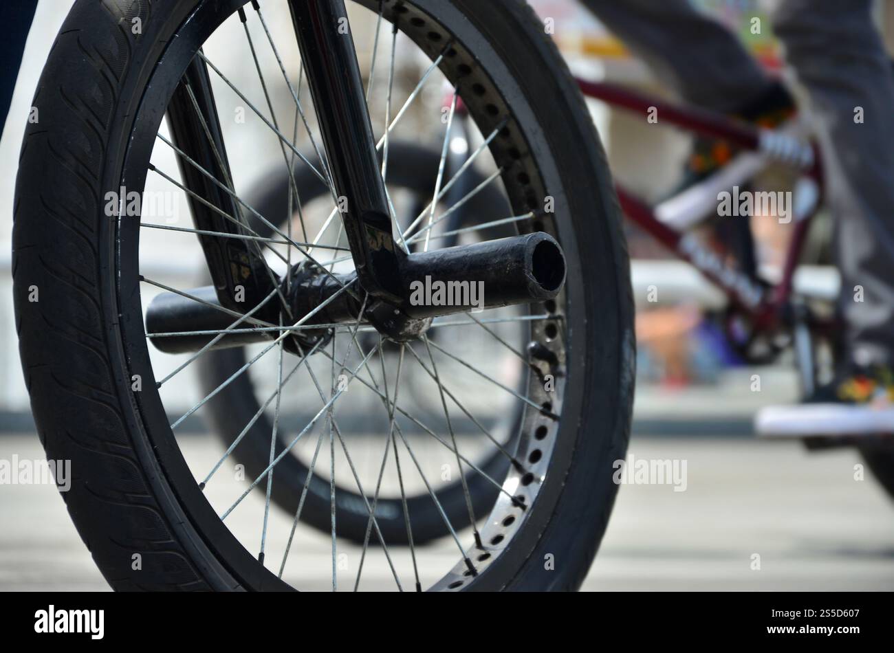 Une roue de vélo BMX dans le contexte d'une rue avec des coureurs cyclistes brouillée. Extreme Sports Concept Banque D'Images Une roue de vélo BMX dans le contexte d'une rue avec des coureurs cyclistes brouillée. Extreme Sports Concept Banque D'Images